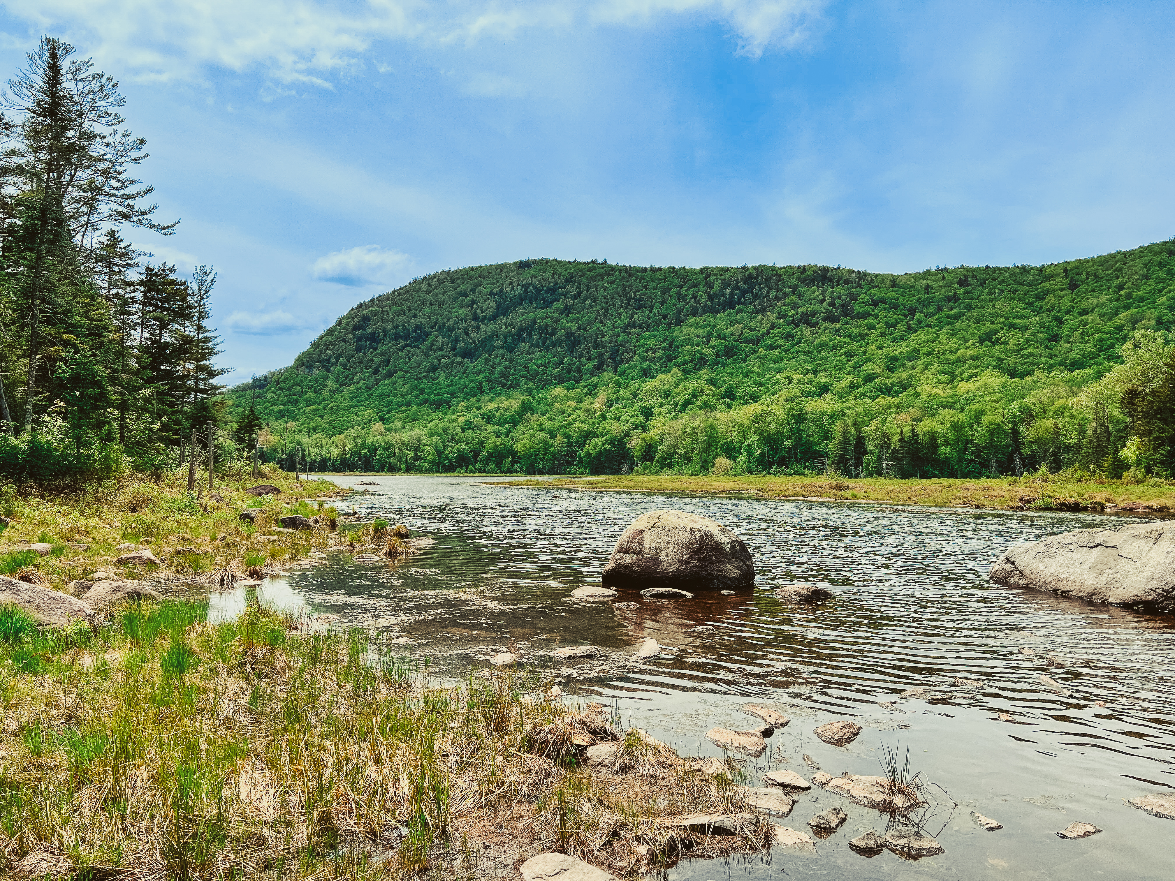 A panorama of a pond with a short, flat mountain in the background.