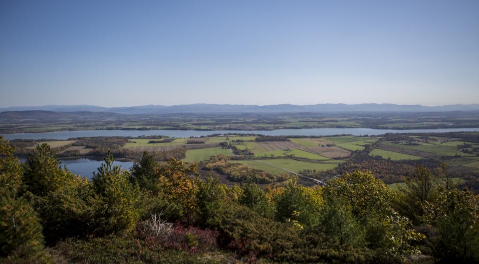 A view from above of wide open farmland with a lake through it.
