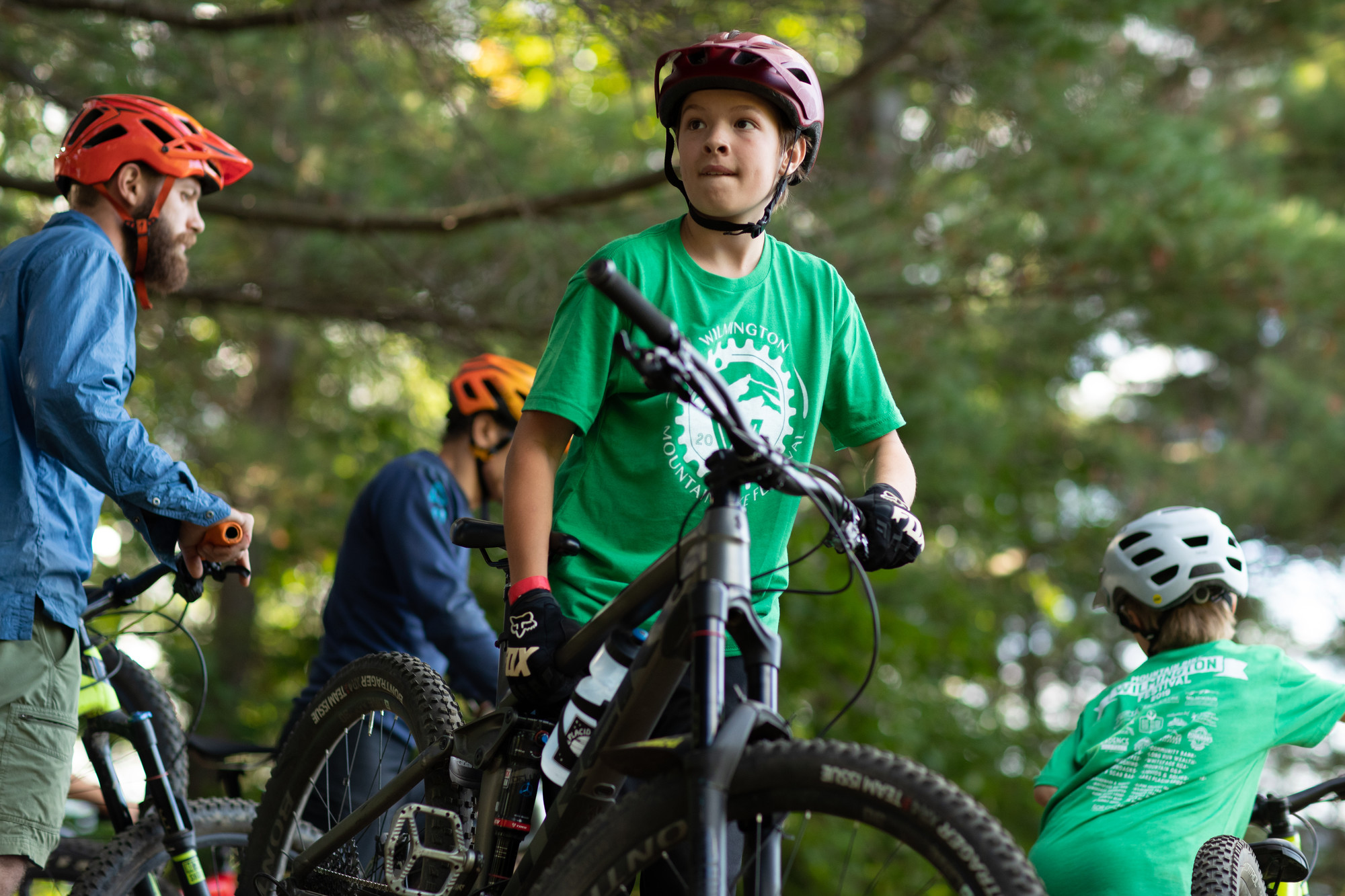 A boy stands with his bike amongst other riders