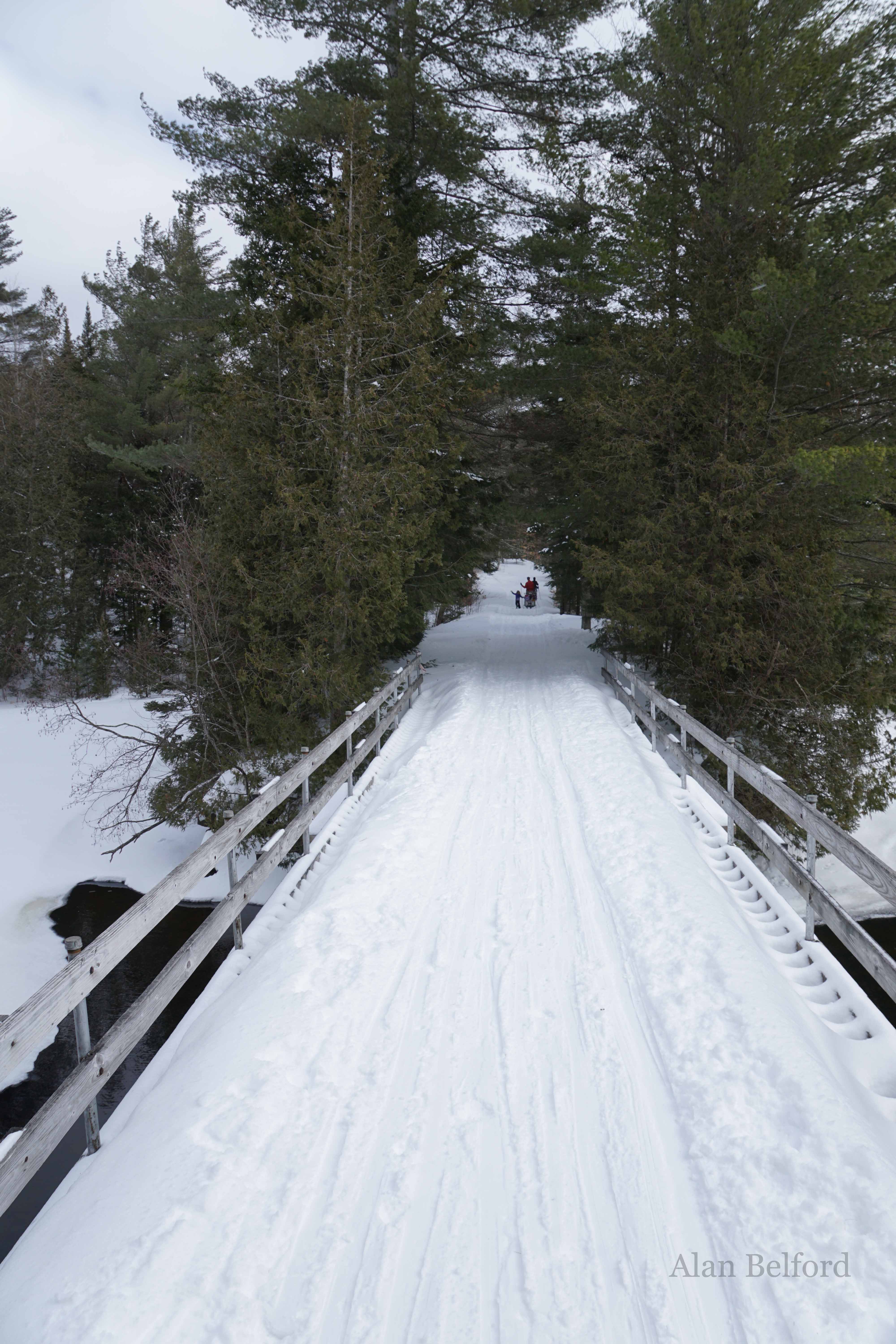 I paused at the bridge over the finger of Newcomb Lake while a little girl hitched a ride on the sled her father was pulling ahead.