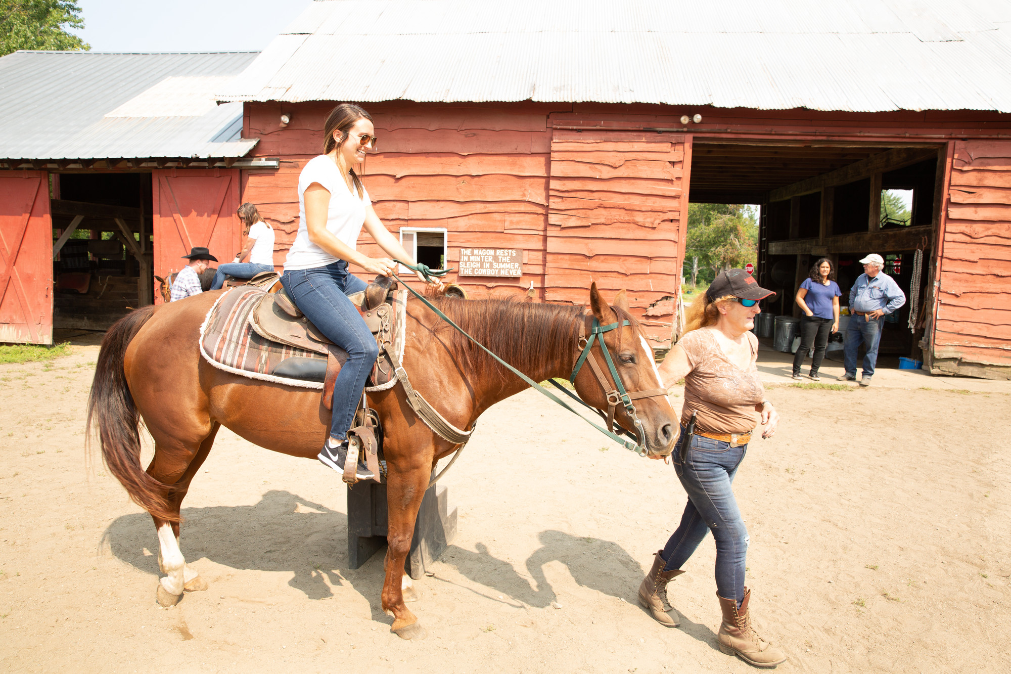 a woman guides a girl on horseback.