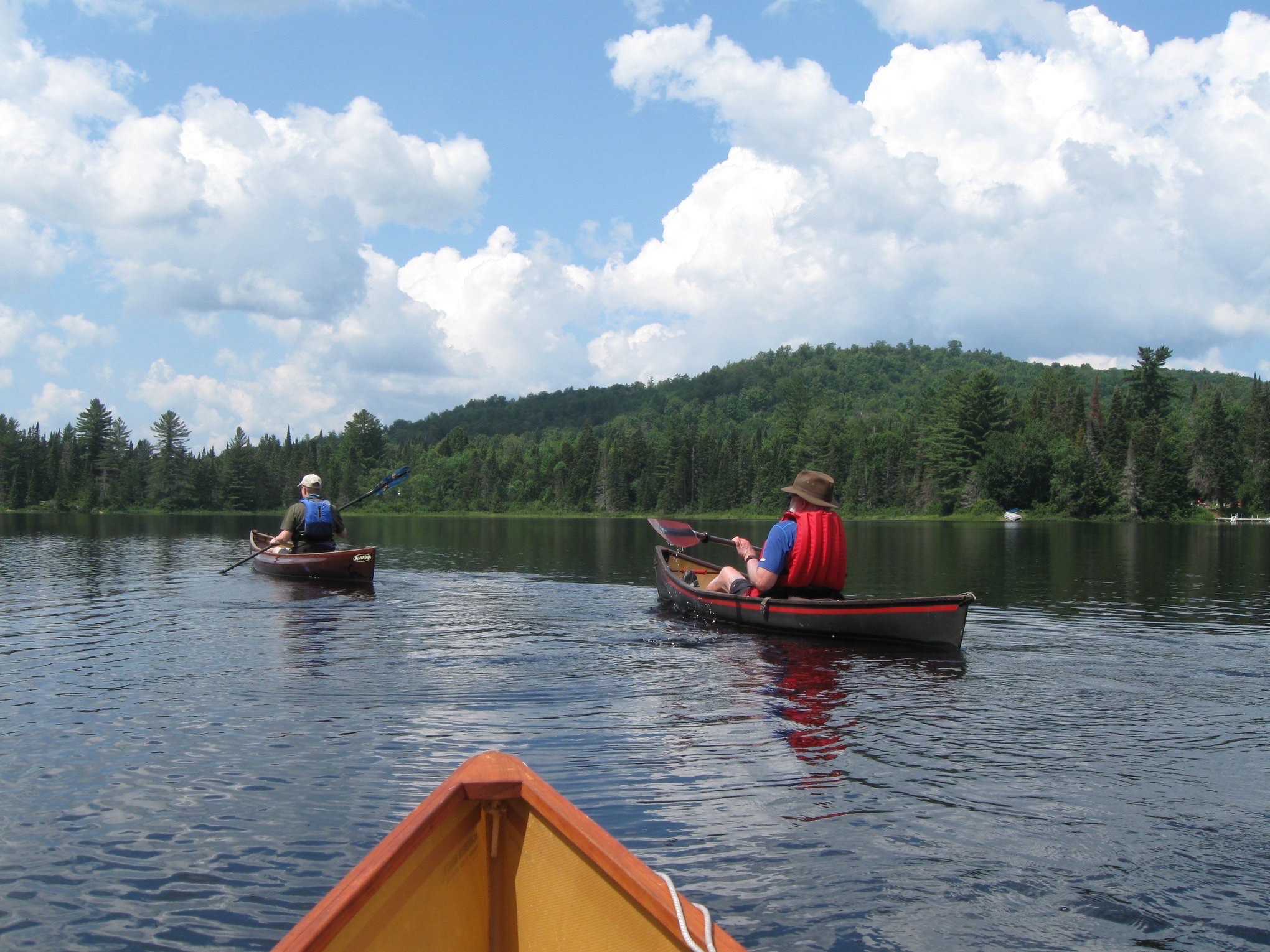 Canoeists on a tranquil lake with mountains beyond.