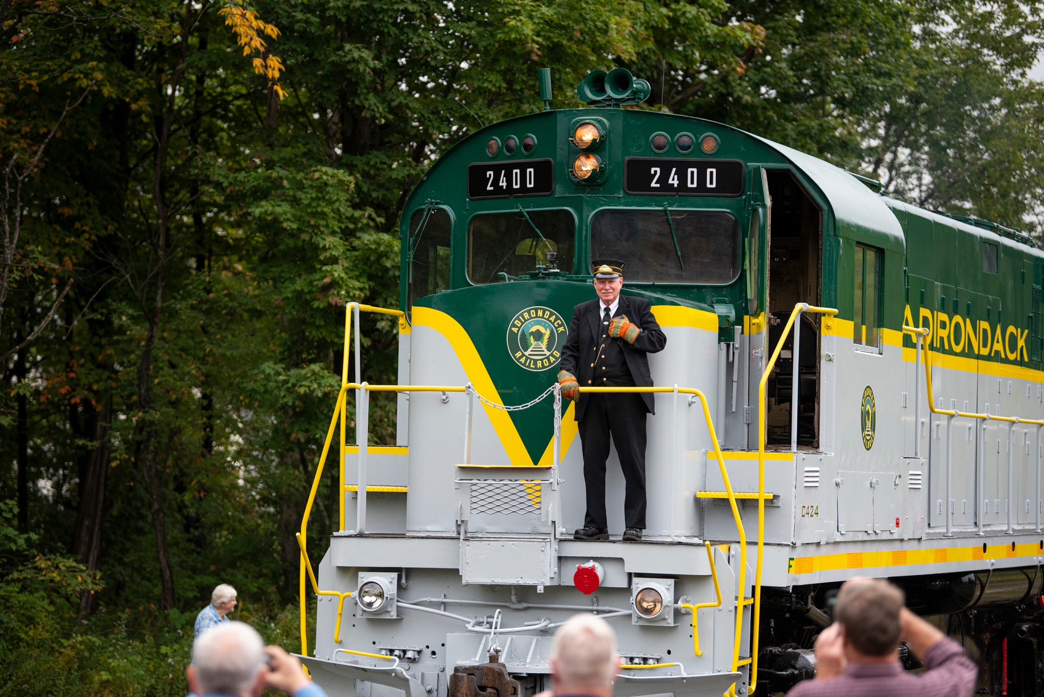 A train conductor smiles from the front of a locomotive.