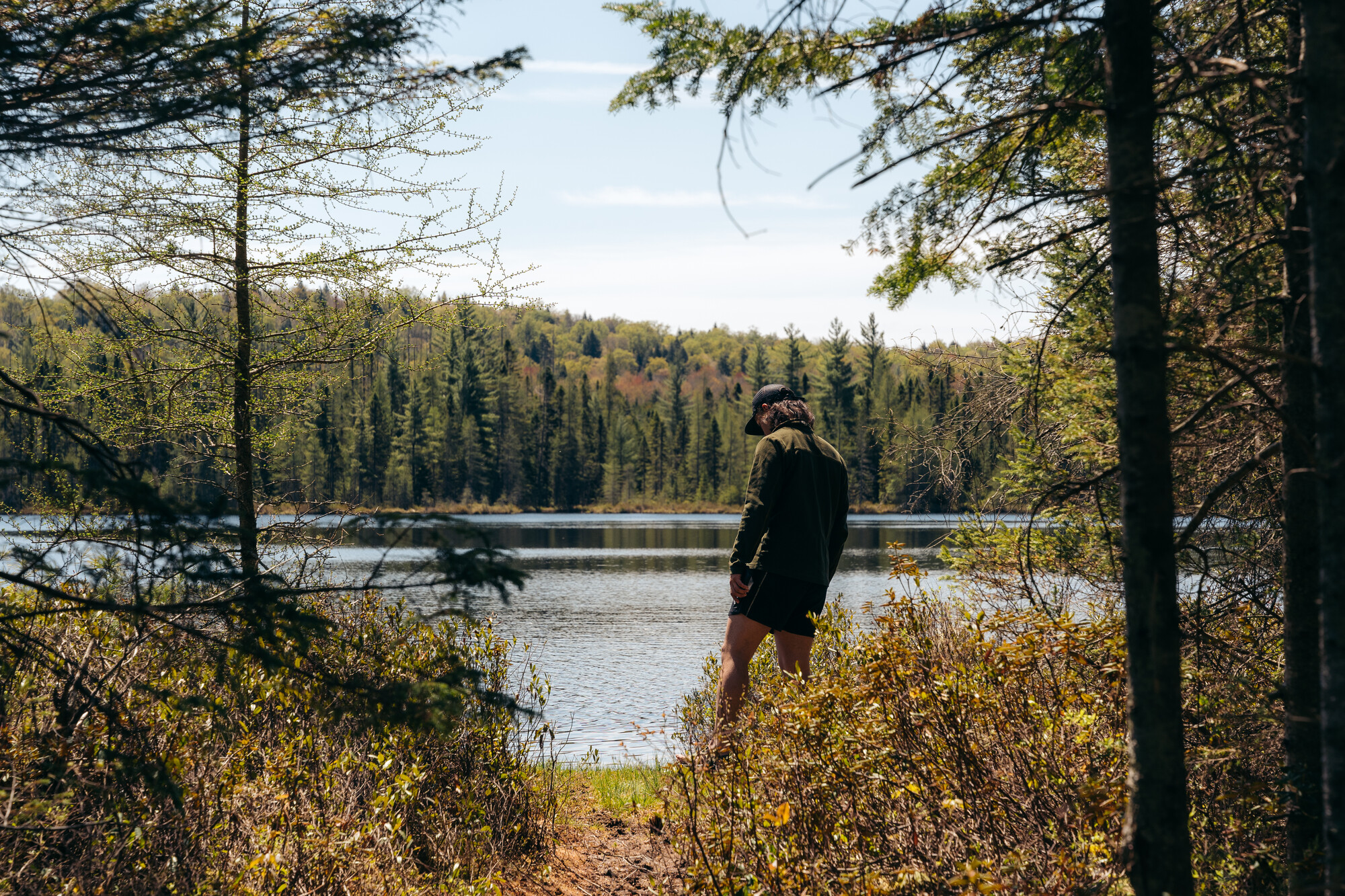 A hiker looks out across a small pond