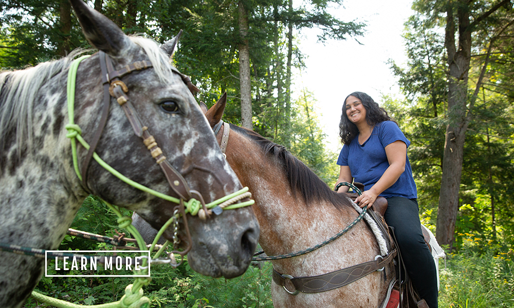 A smiling woman on horseback.