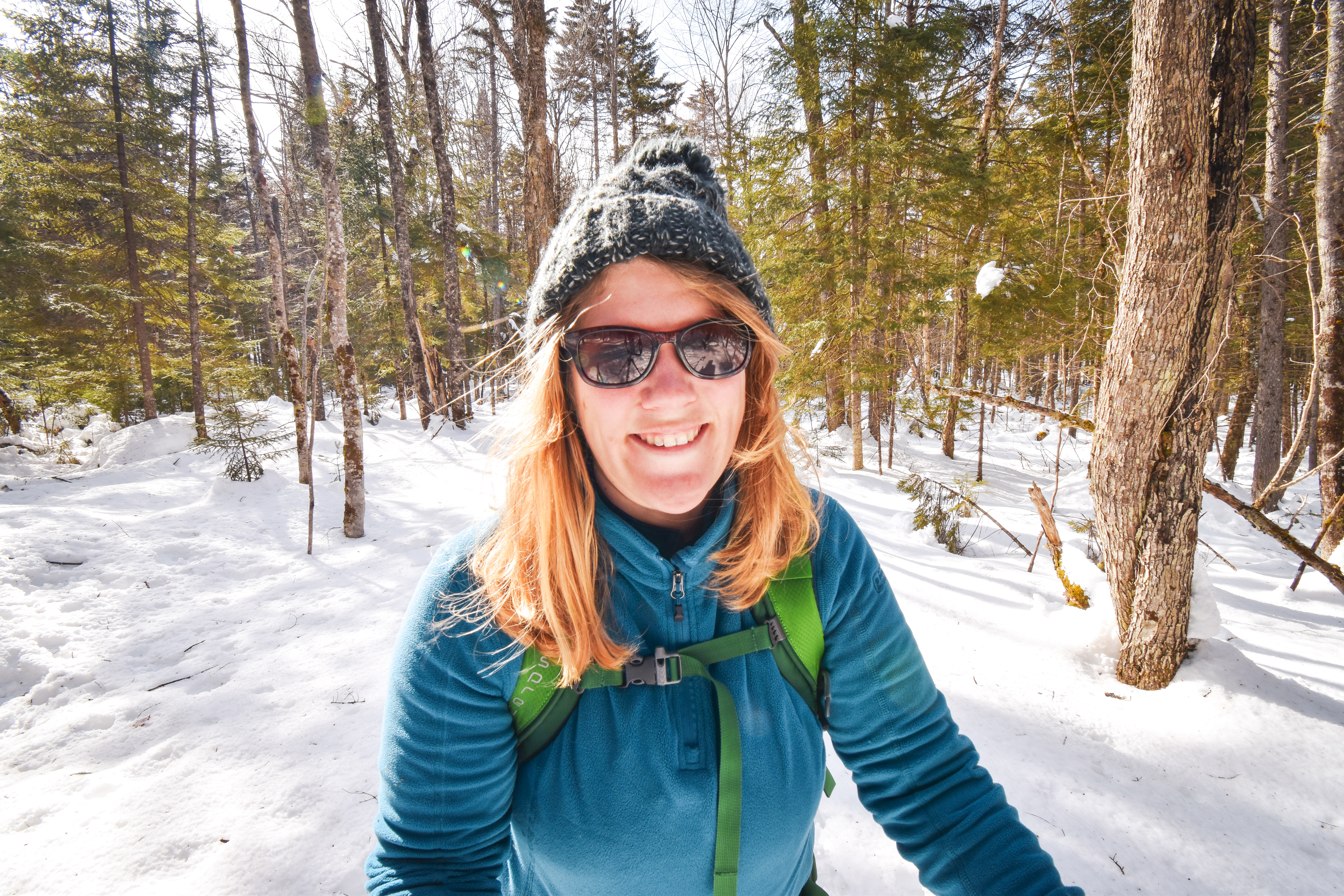 A beautiful woman smiling because she's out skiing.