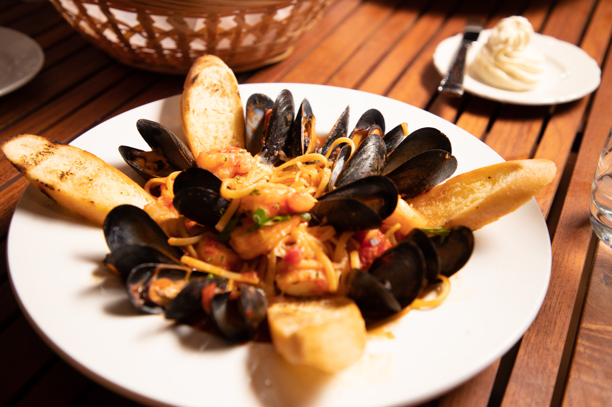 a plate of muscles, baguettes, and spaghetti.