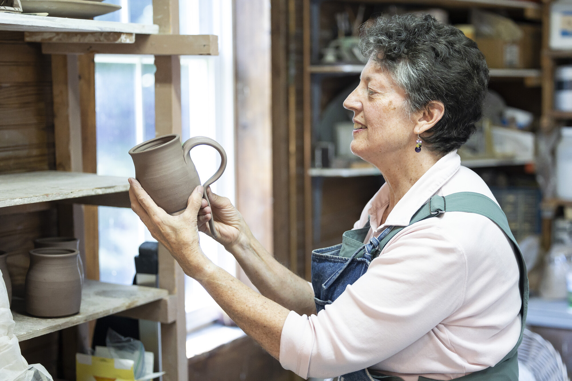 A woman holds a piece of pottery. 