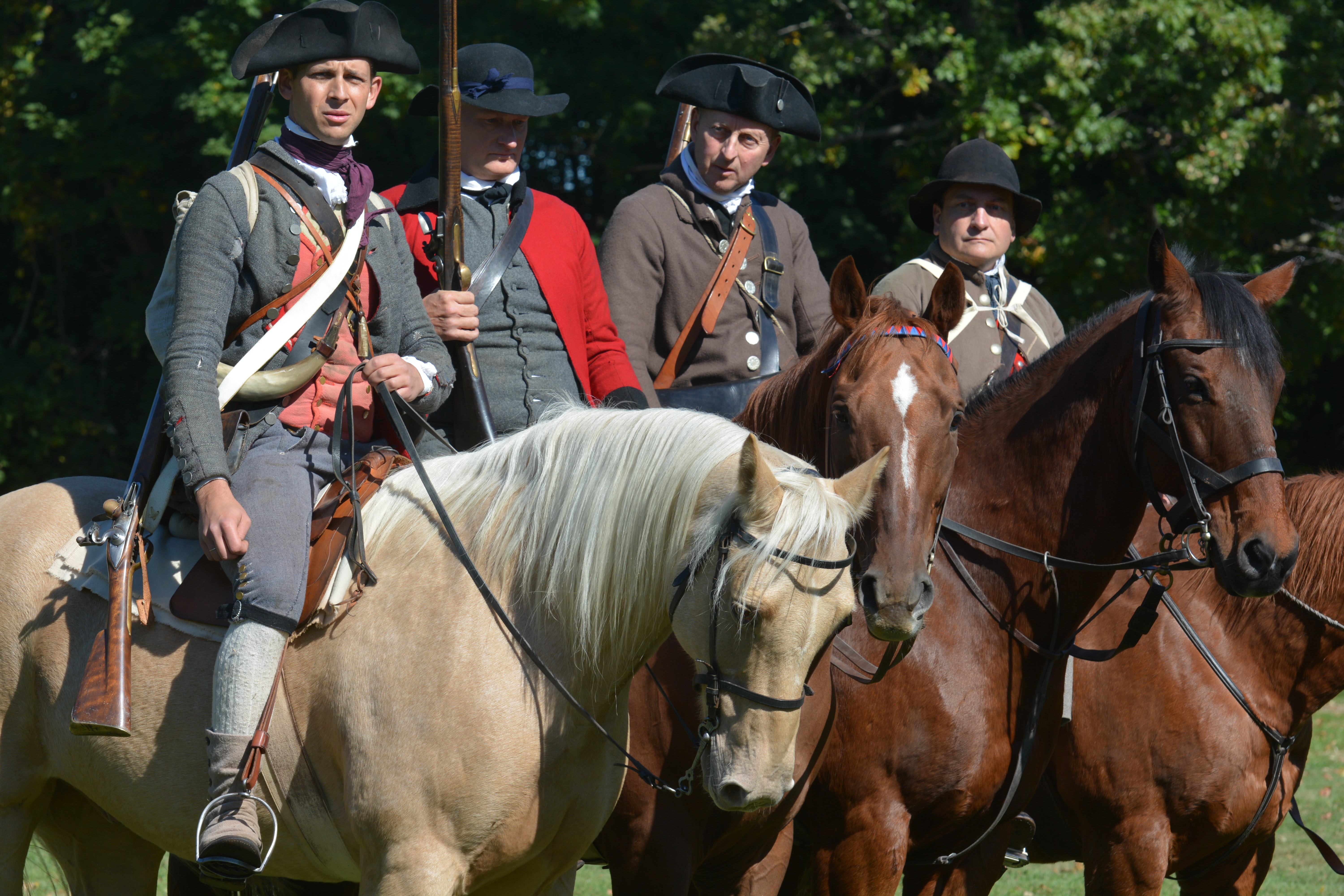 Men dressed in period clothing ride horses as they re-enact a historic battle