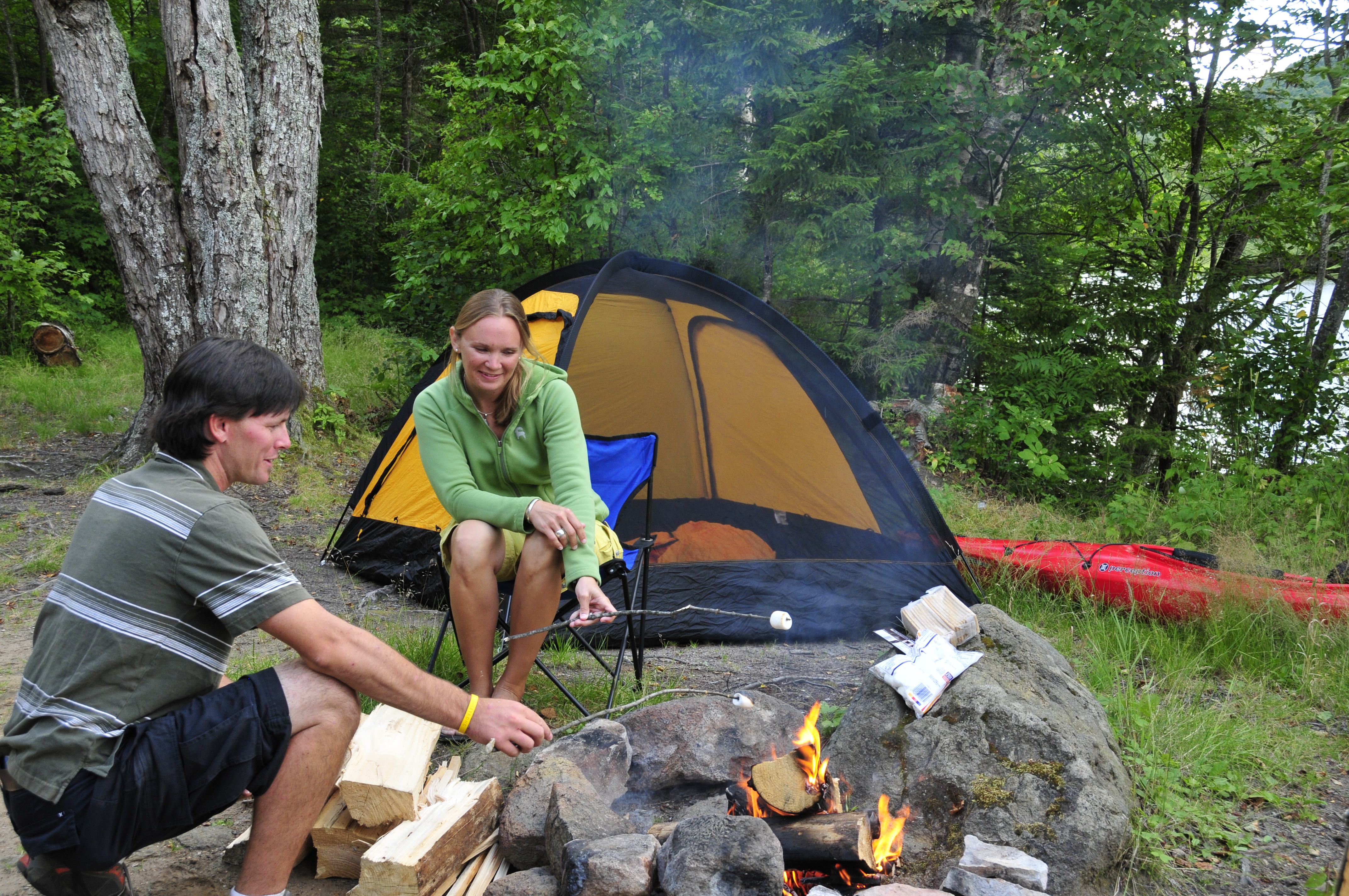 A couple roasts marshmallows over a fire at Cedar River Flow in Moose River Plains