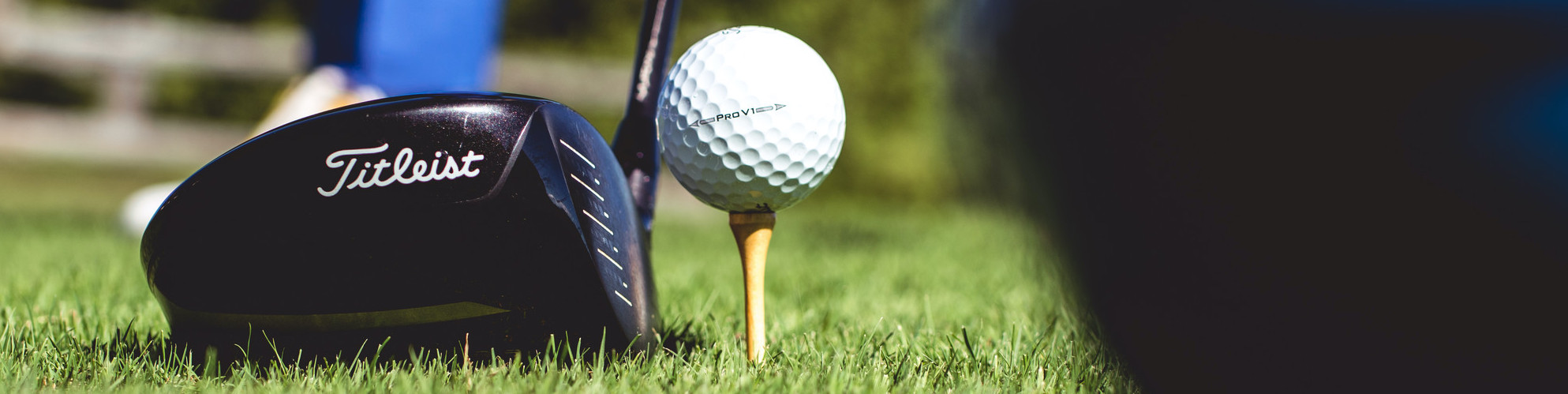 A golf ball and driver ready for tee off.