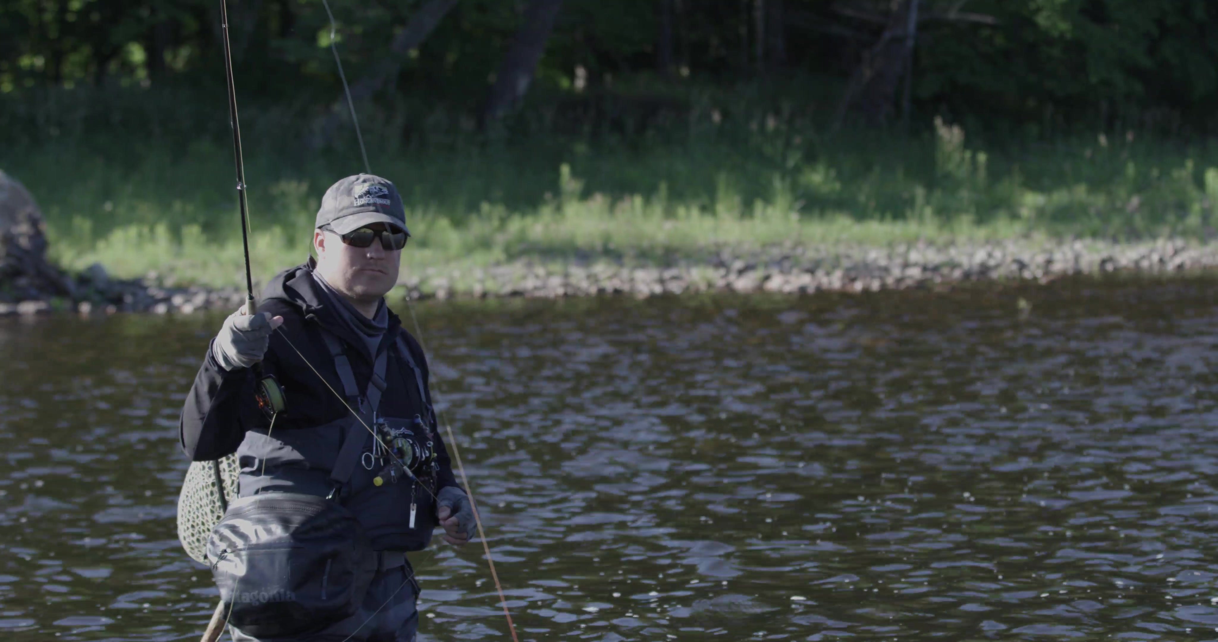 The fisherman casts. You can see the river gently flowing all around him.