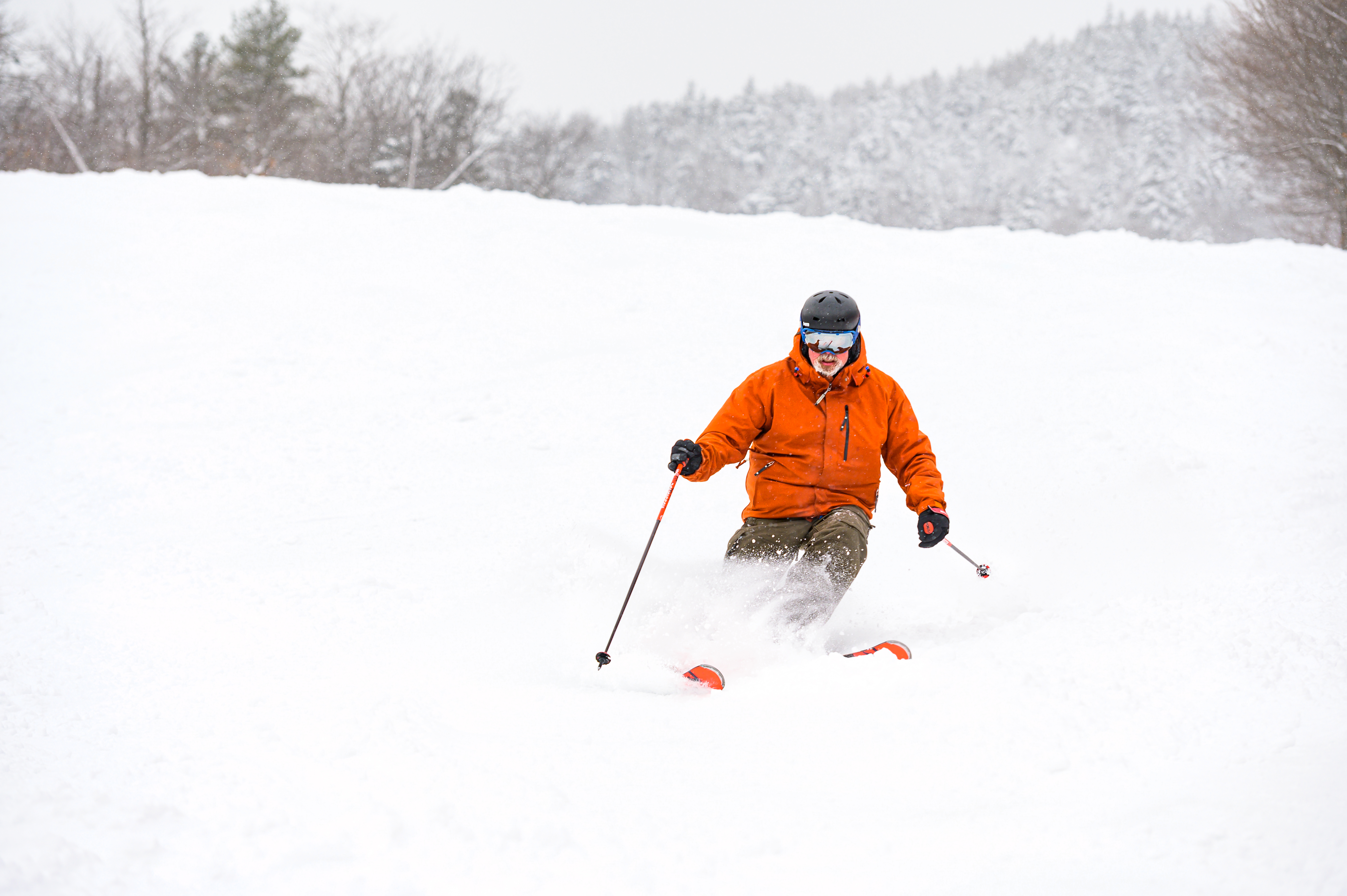 A man downhill skiing on a powder day.