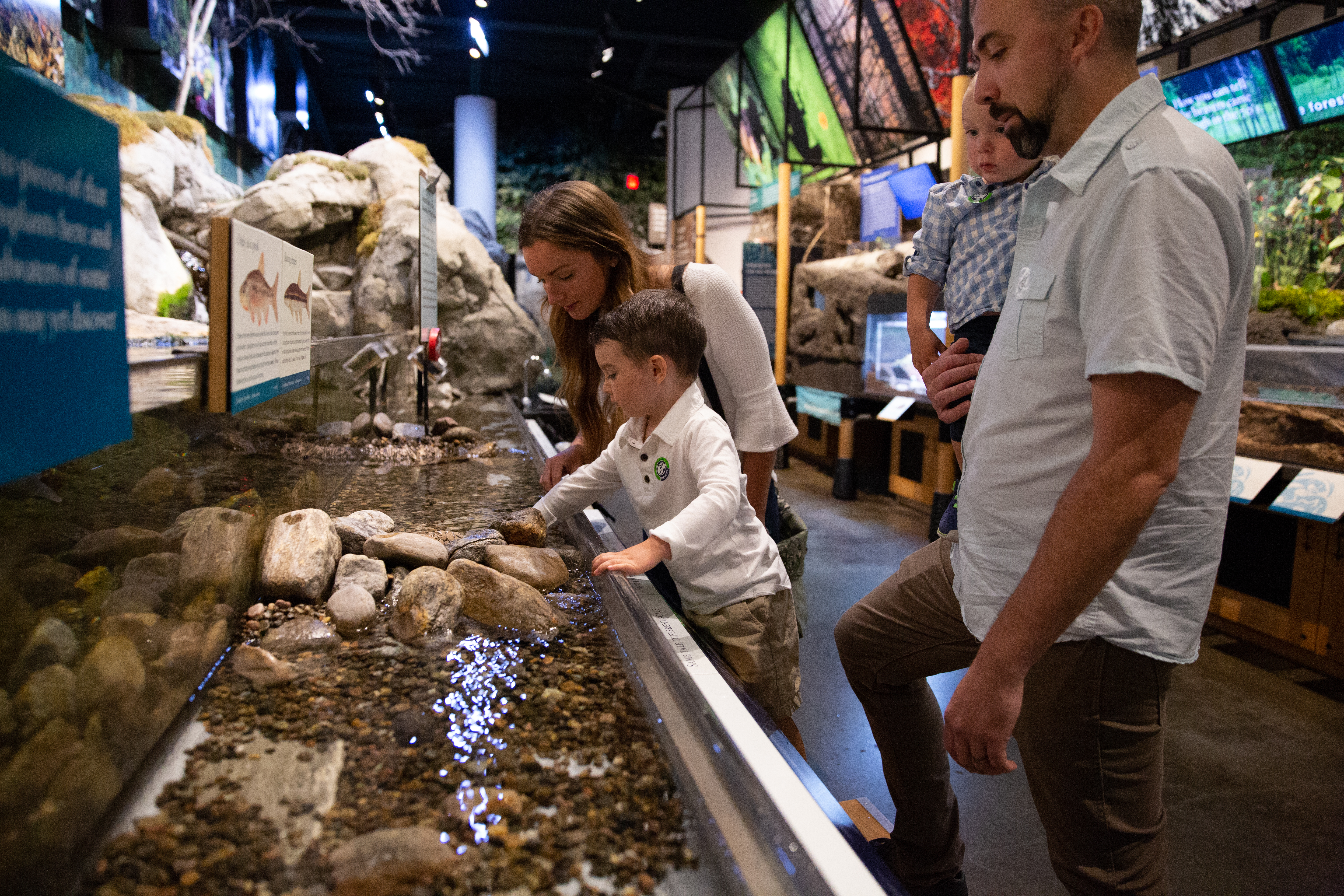 A child and his parents explore a water exhibit at a natural museum.