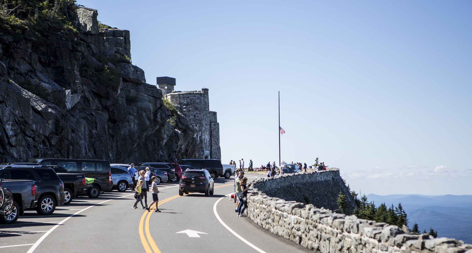 Cars park along the side of the Whiteface Veteran's Memorial Highway as visitors look out upon a view of the Adirondack Mountains.