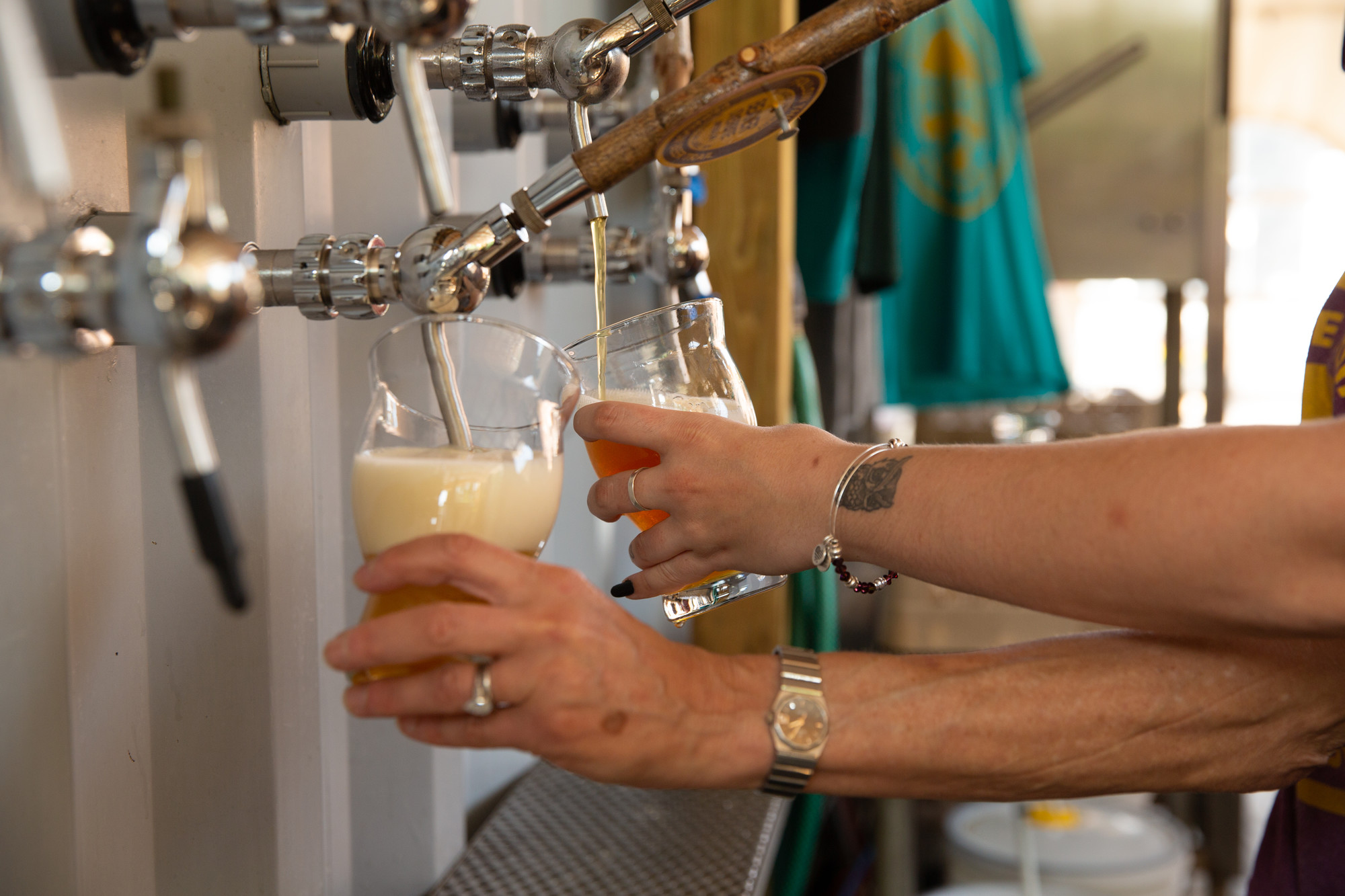 Two people fill pint glasses from taps