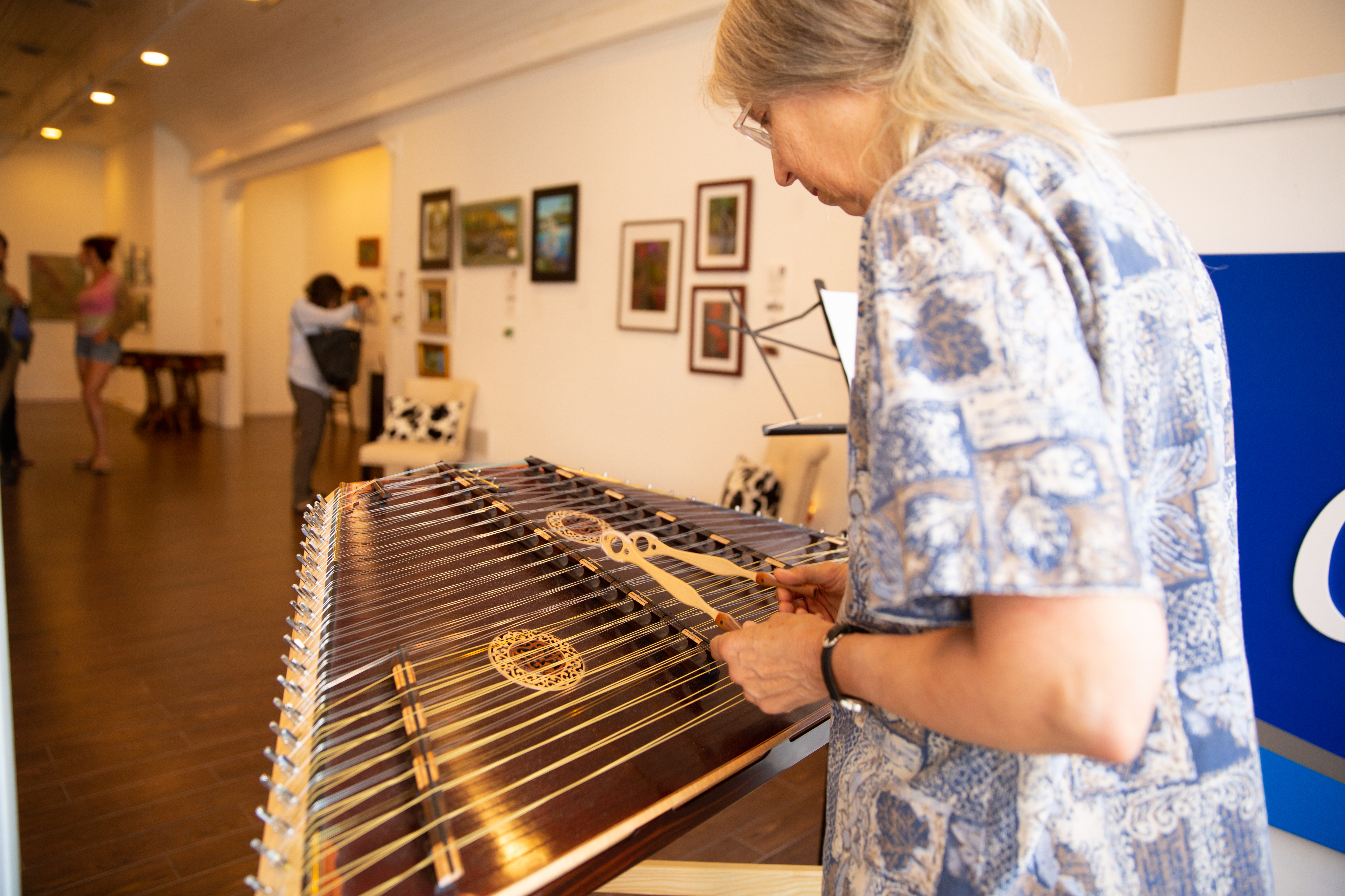 A woman plays a hammered dulcimer at an arts festival