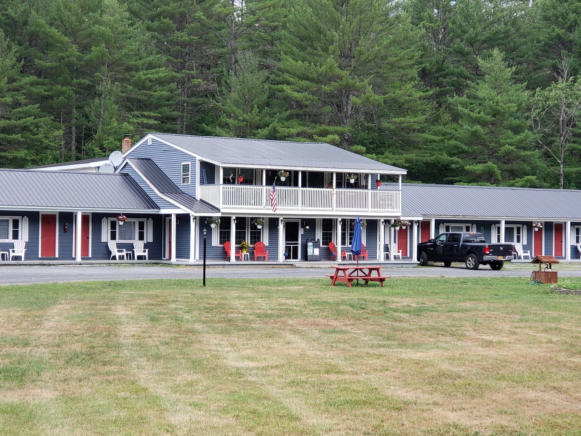 Exterior view of a tidy blue motel backed by forest.