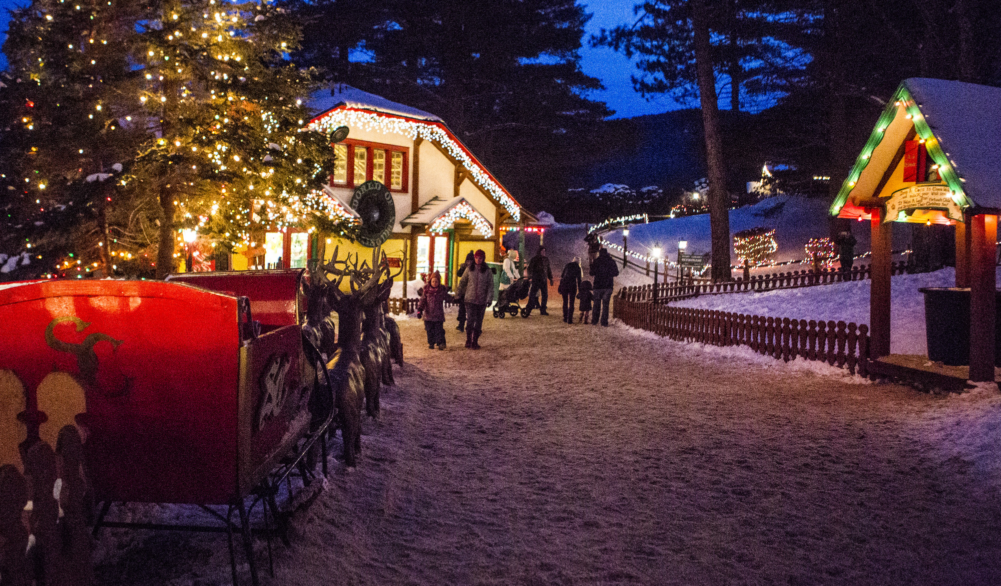 Families walk around santa's workshop in winter.