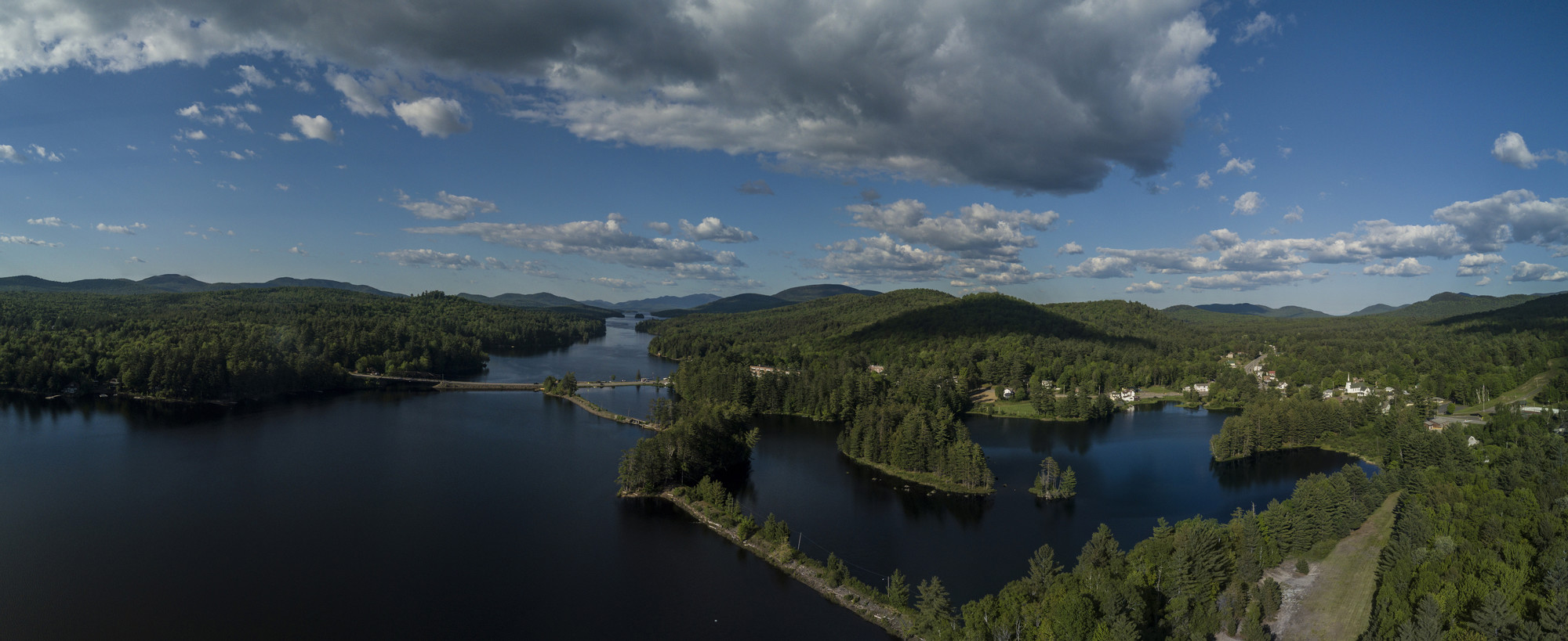 A green, summery view from above of Long Lake, mountains, and summer trees.