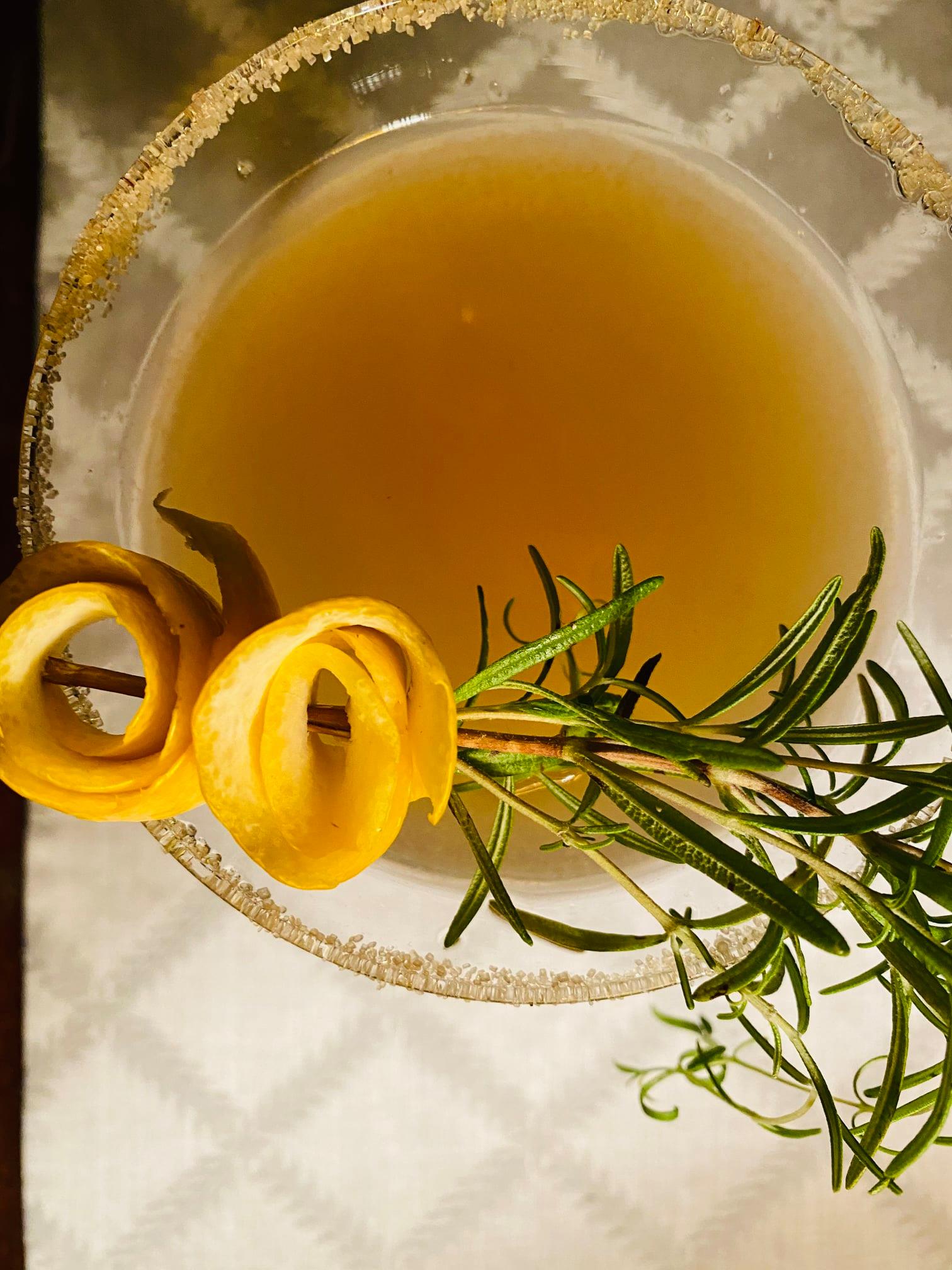 Extreme close-up of a cocktail garnished with thyme and lemon.