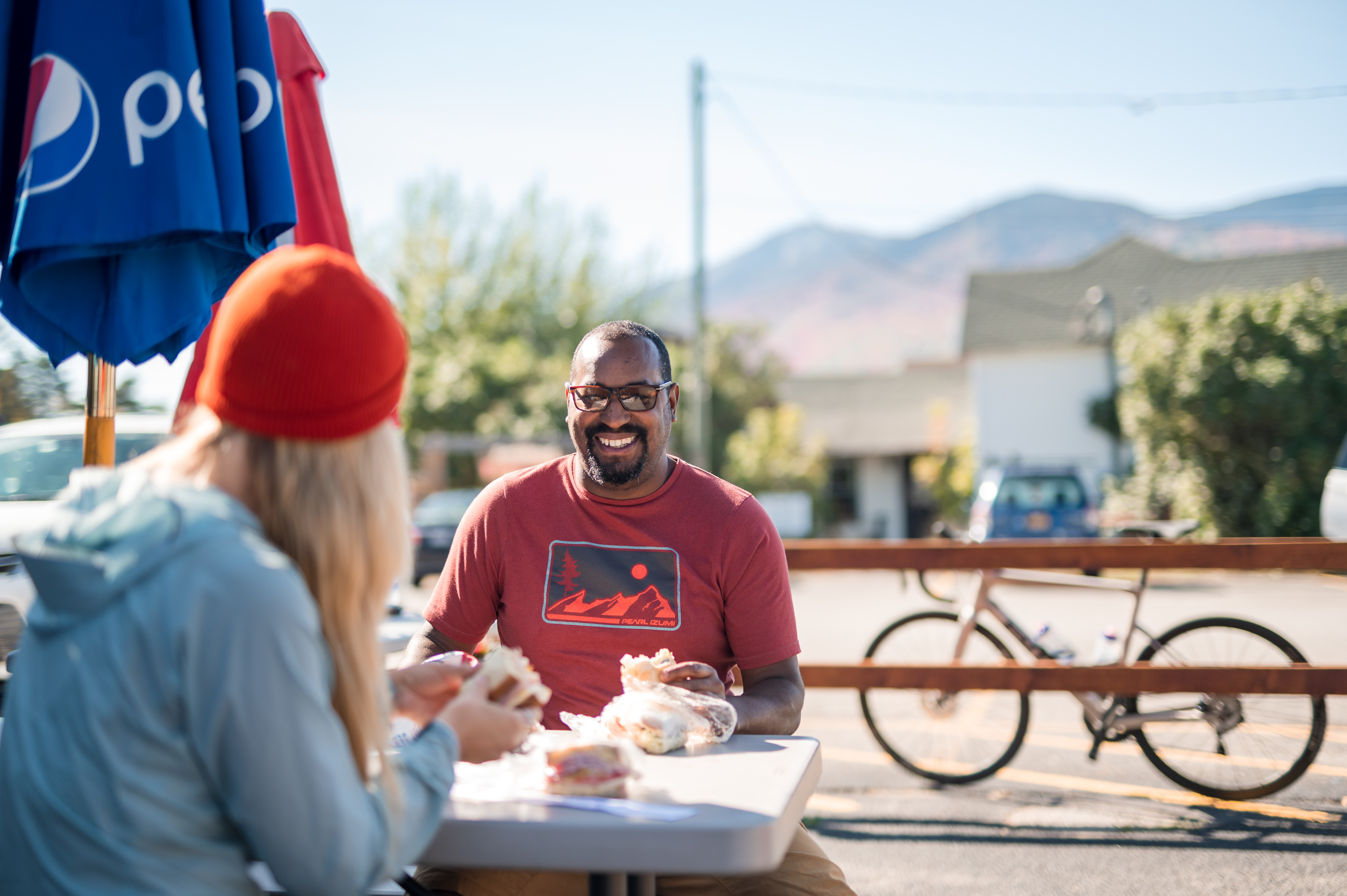 two people eating sandwiches on a picnic table