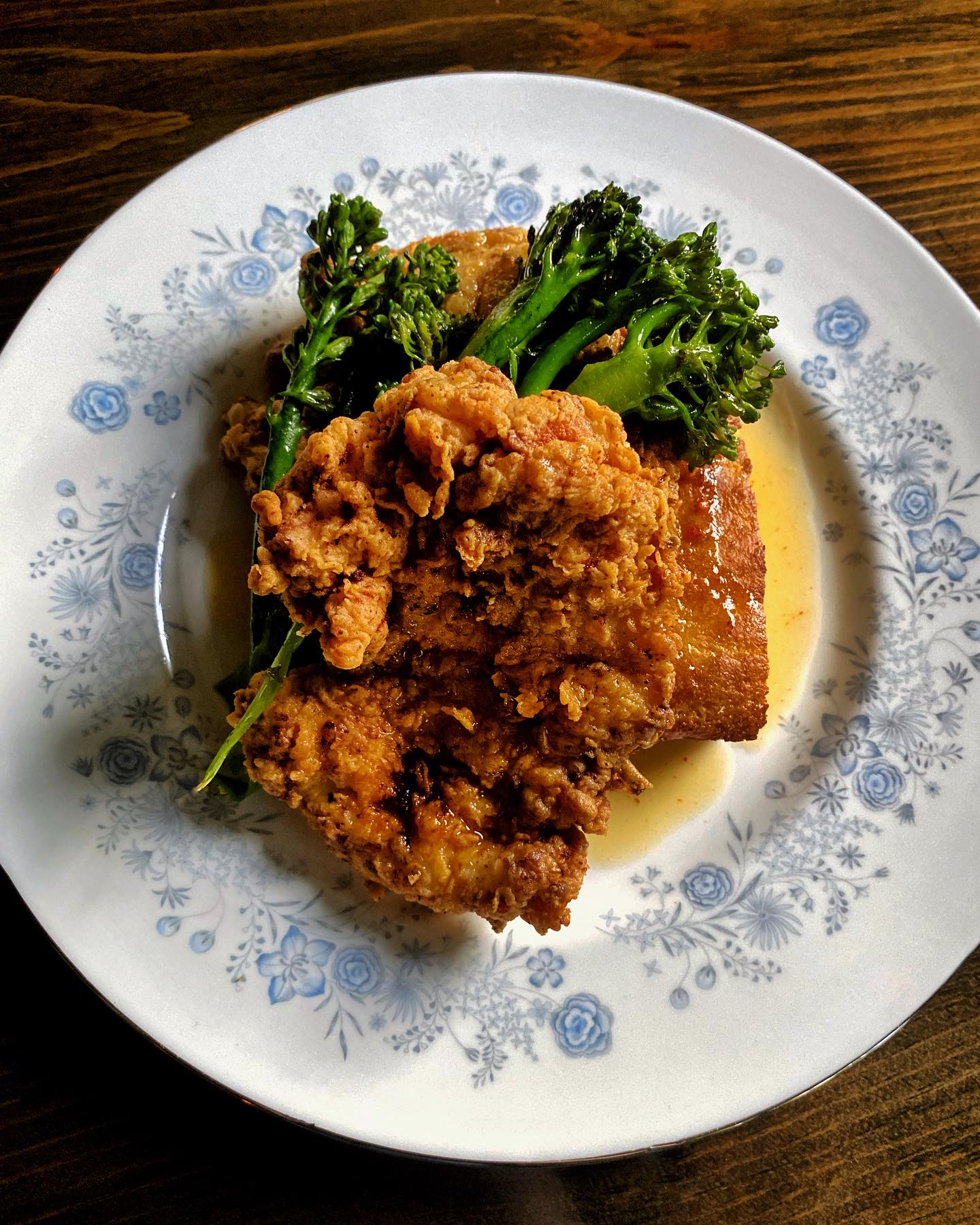 A fried chicken dinner rests on a china plate with a blue design