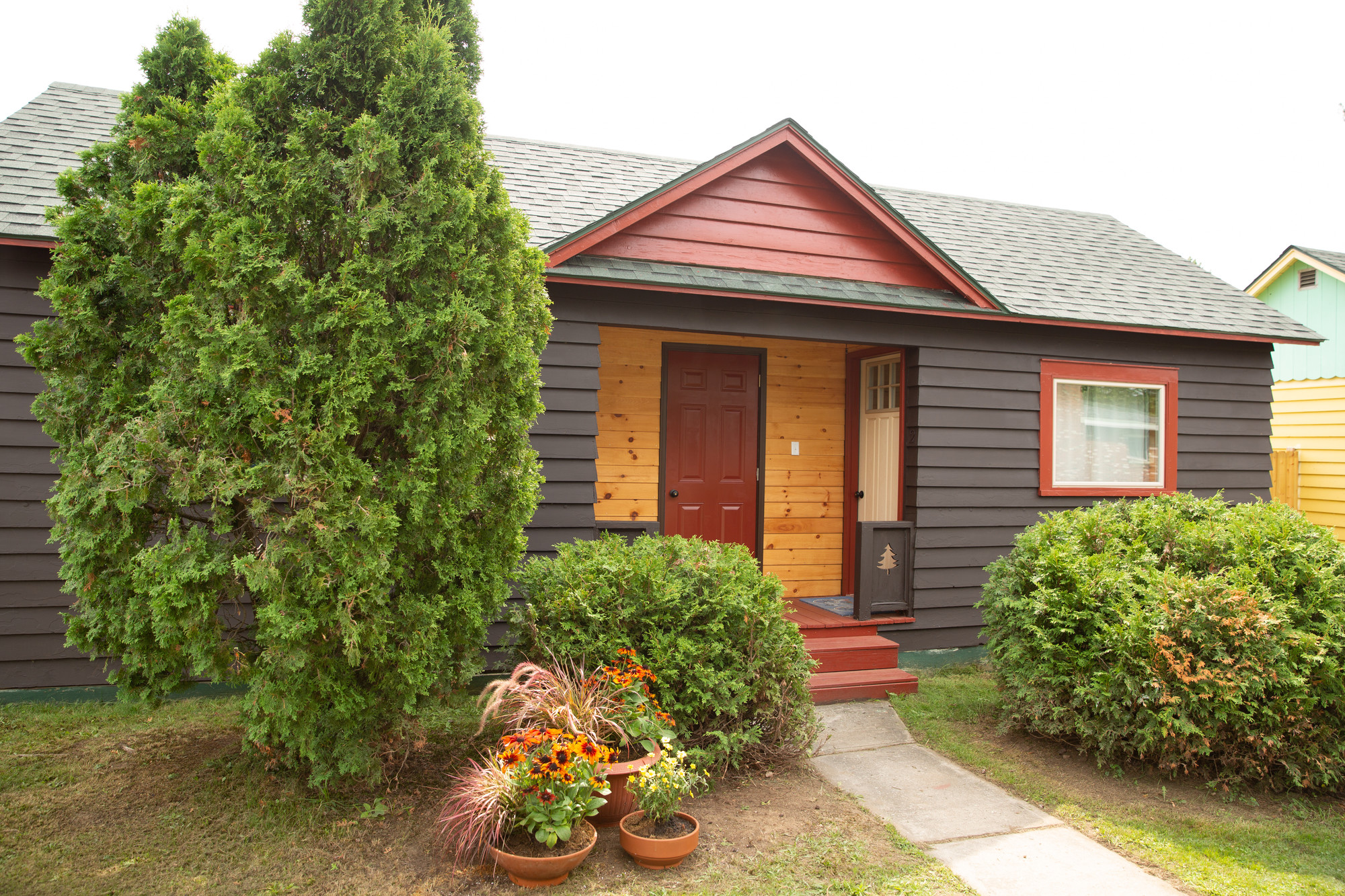 The exterior of a cozy motel cottage, surrounded by fall landscaping.