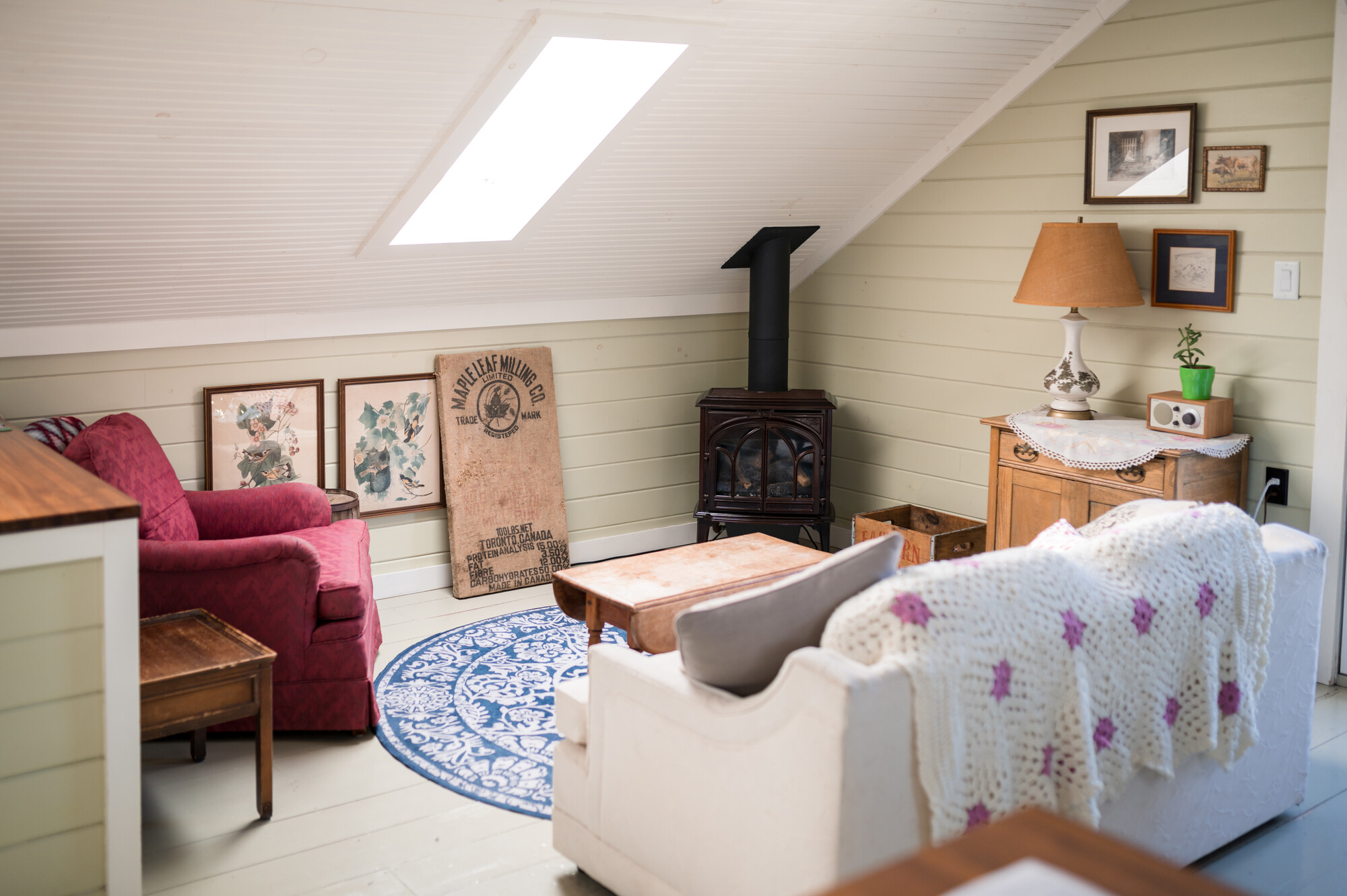A cozy farmhouse living room, featuring natural light, antiques, and a woodstove amid the furnishings.