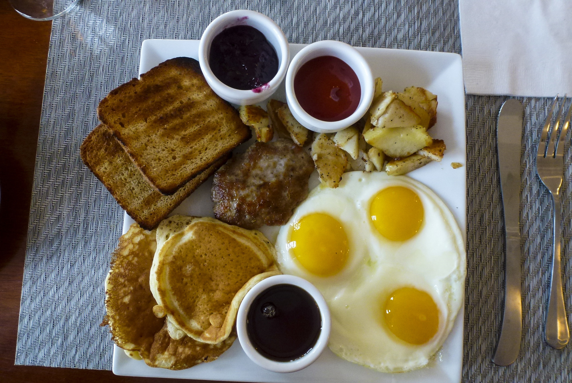 A plate full of breakfast food, including eggs, pancakes, and toast.