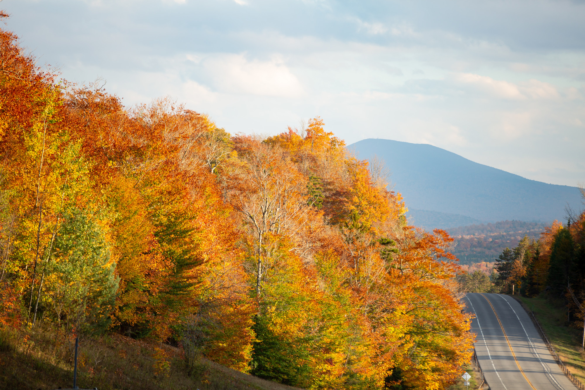 A stretch of road between Tupper Lake and Long Lake, with brilliant foliage and Blue Mountain in the distance.