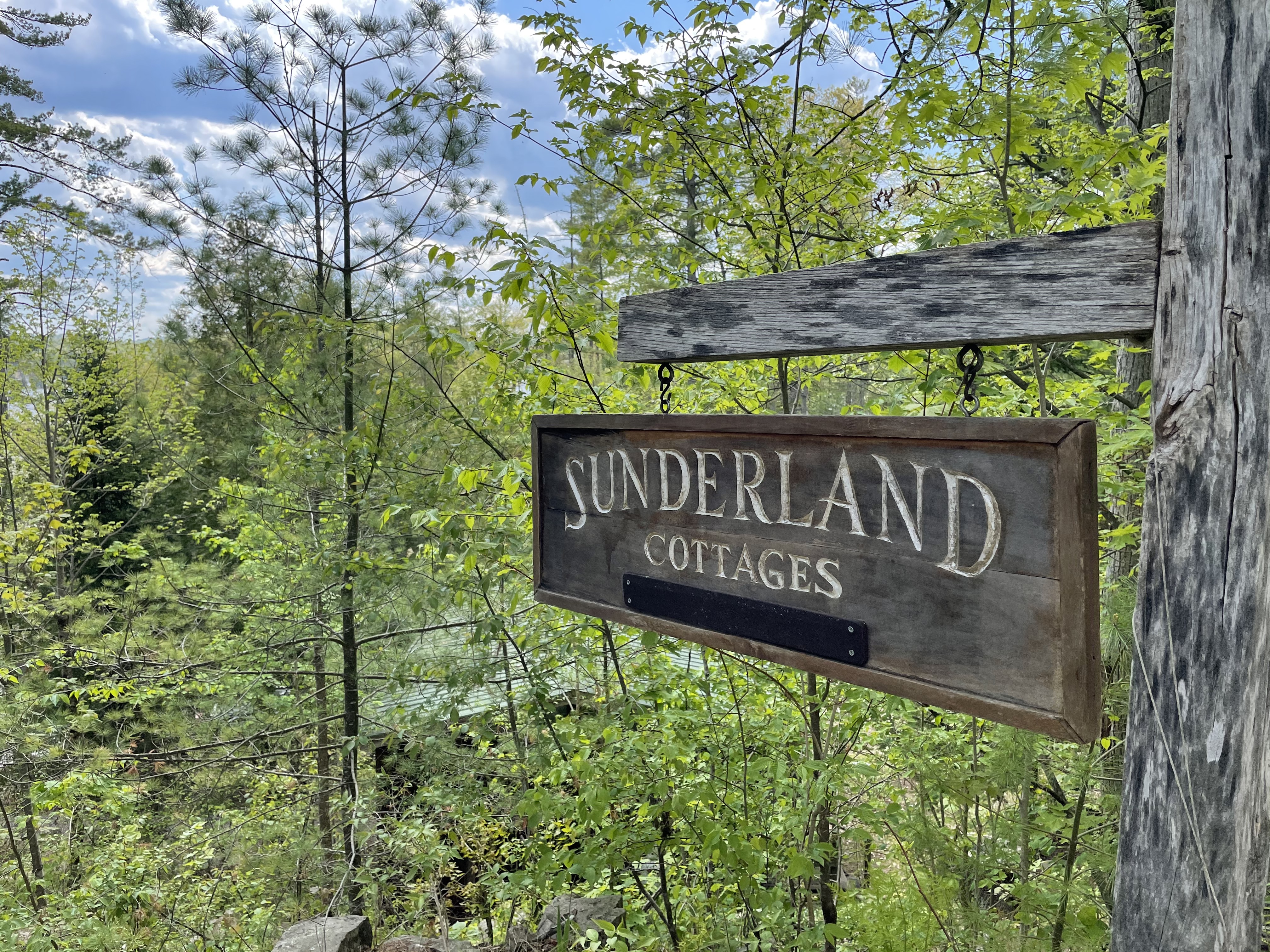 Sunderland Cottages sign in front of trees.