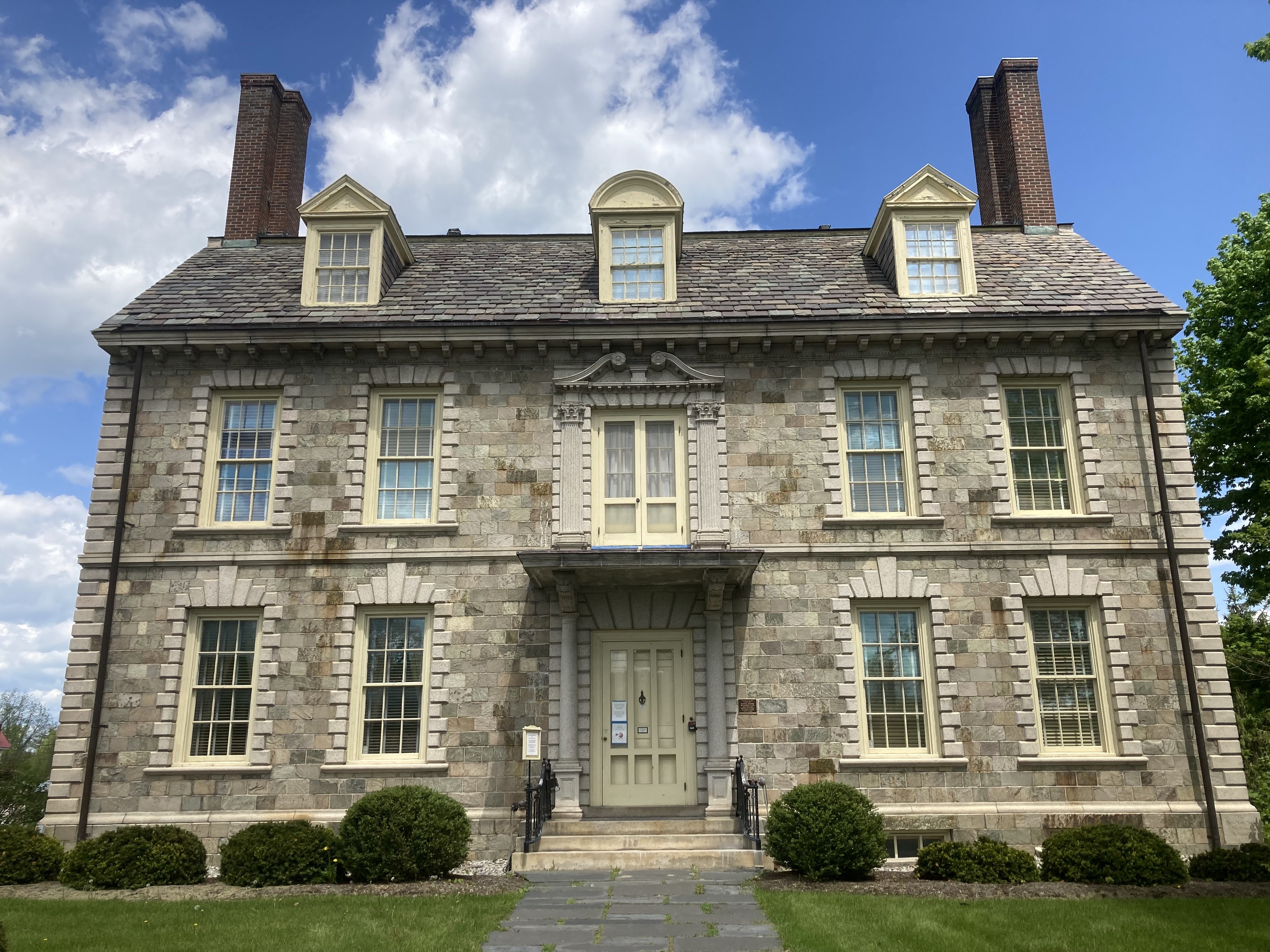 The exterior of a stone, two story, Federal-style home.