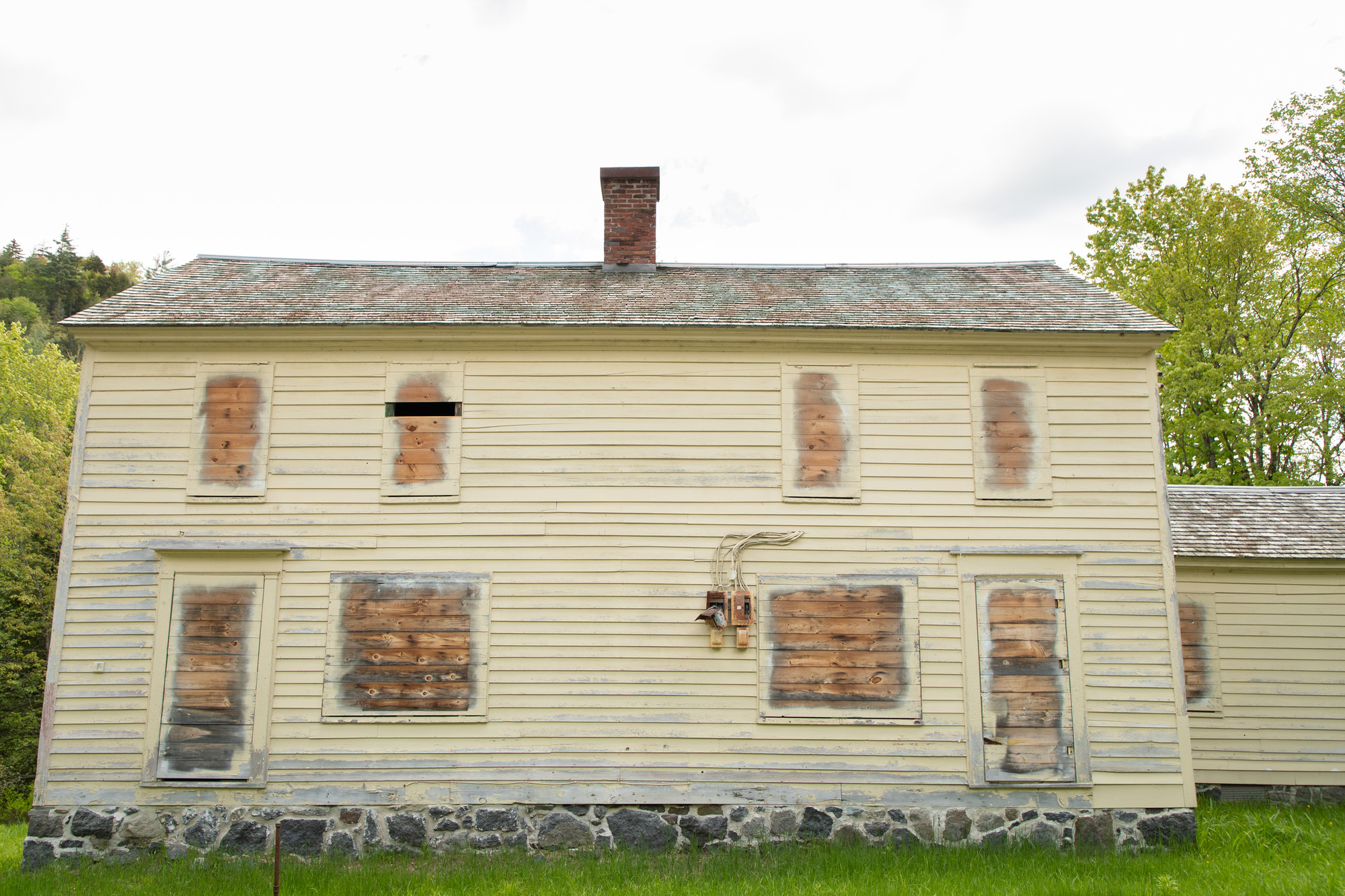 An abandonded up house with yellow paint and boarded up windows