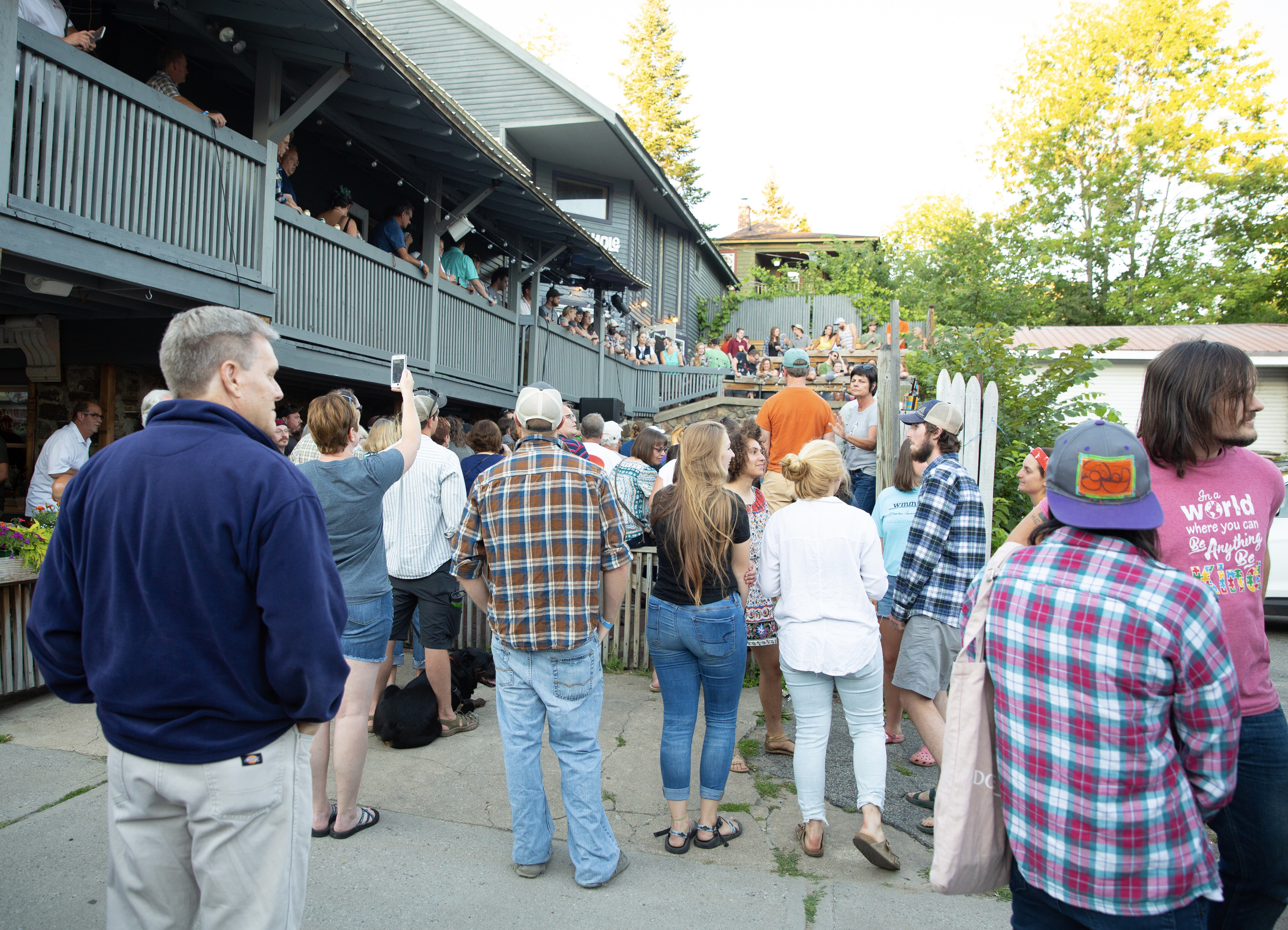 A crowd of people watch a music performance at a small outdoor space.