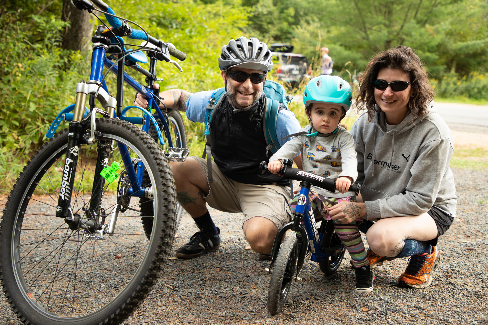 A man and woman crouch for a photo with their small child on a mountain bike. 