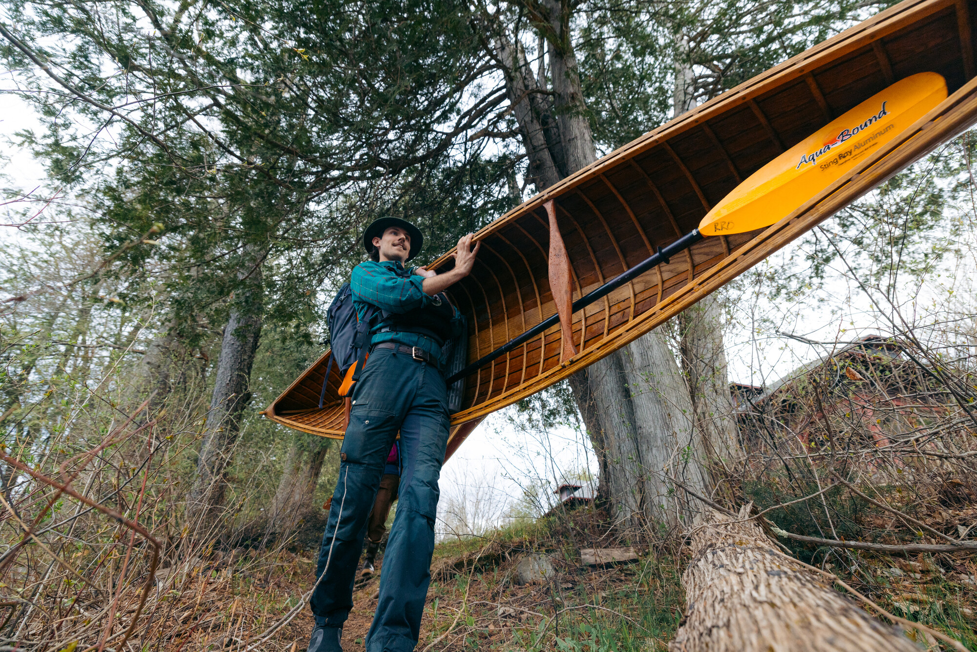 A man carrying a lightweight wooden pack canoe