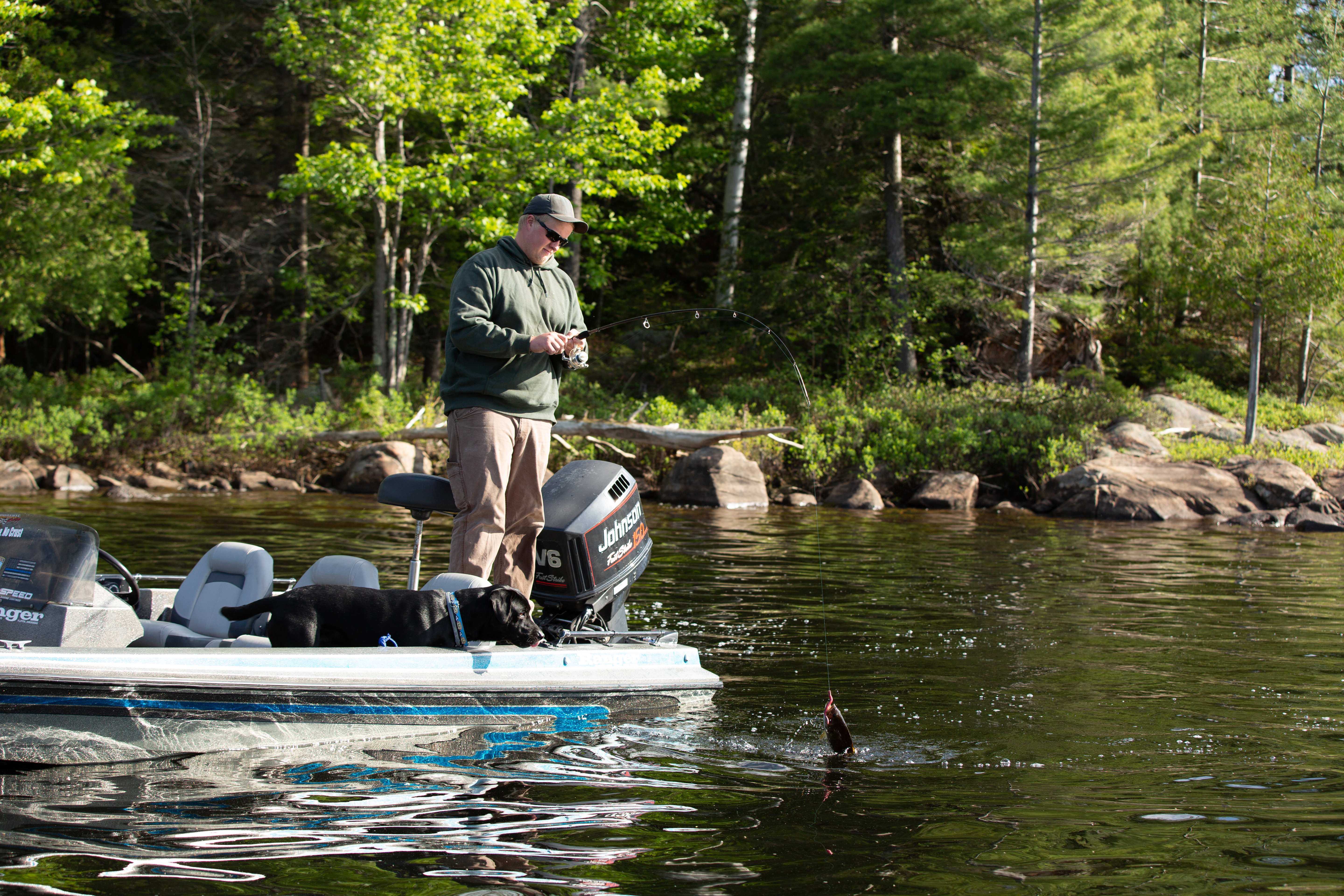 A fisherman on a motorboat reeling in a fish.