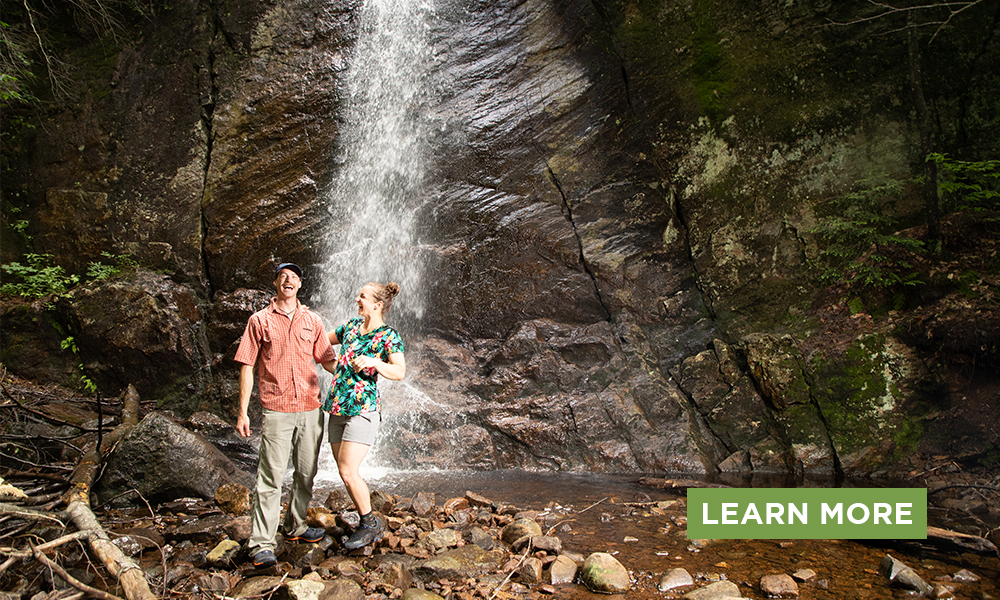 A couple visit a waterfall.