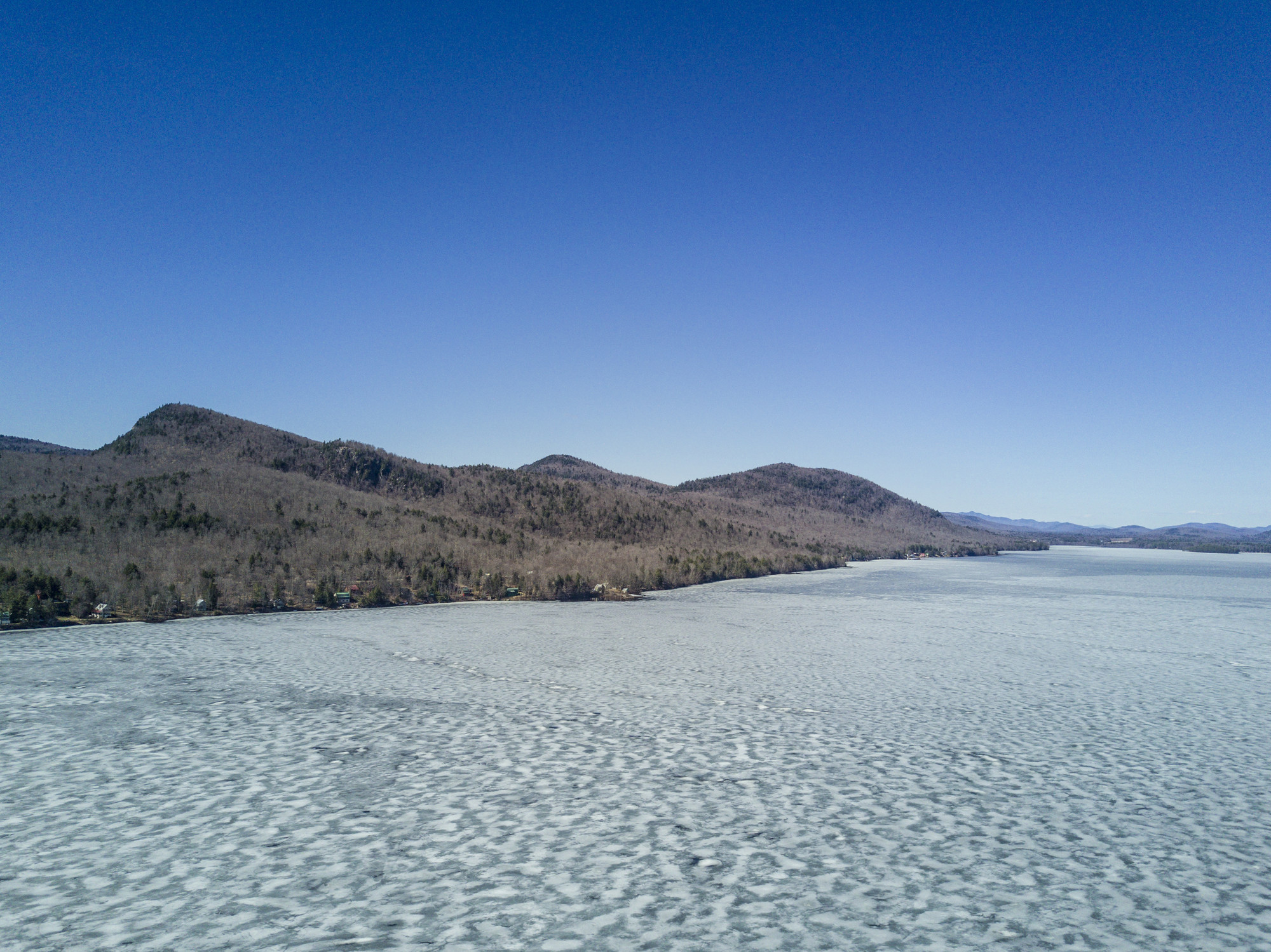 An aerial view of a frozen lake surrounded by wilderness.