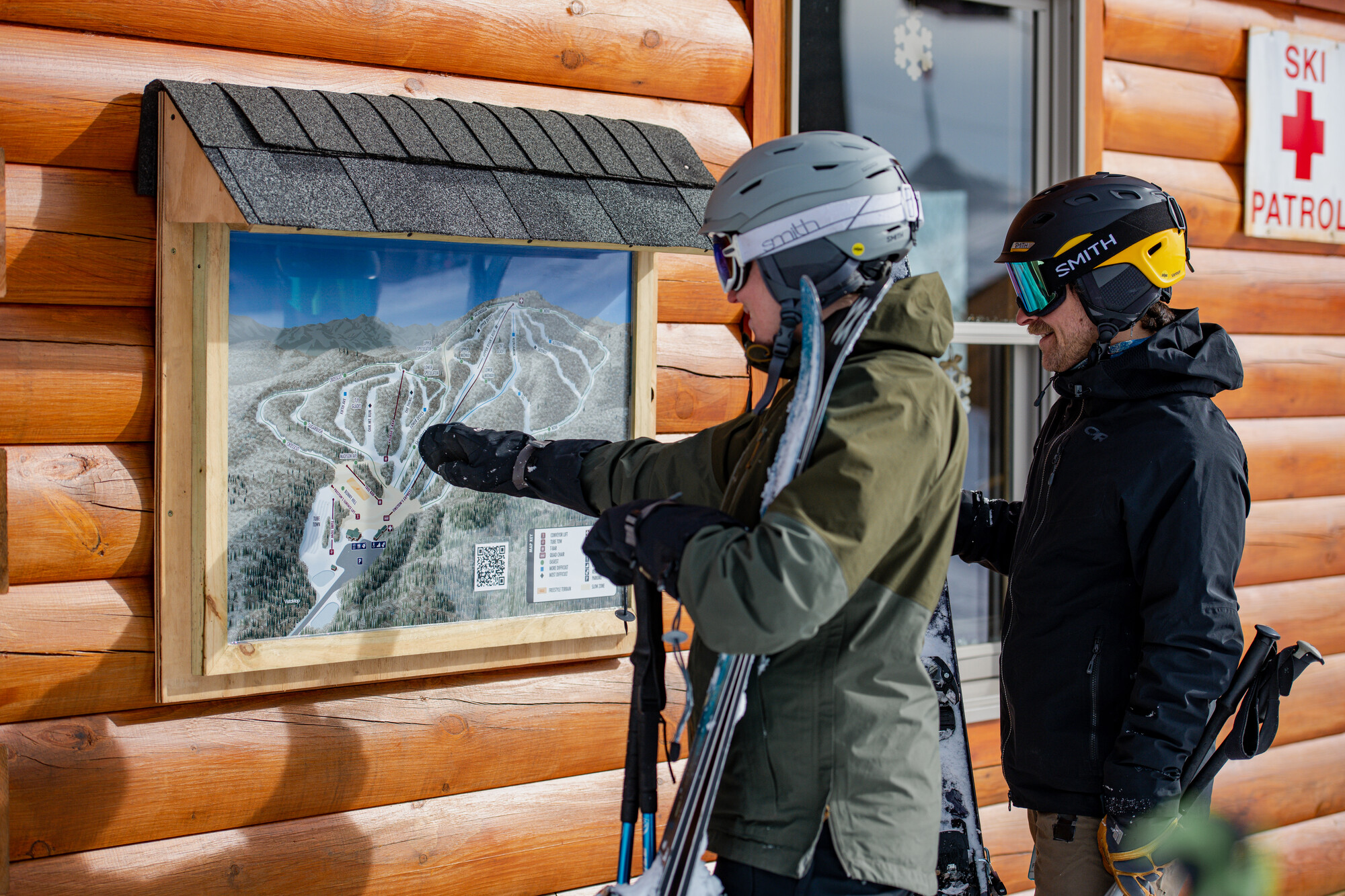 Two skiers look over a ski map posted on the side of a log ski building at Oak Mountain Ski Center in Speculator NY