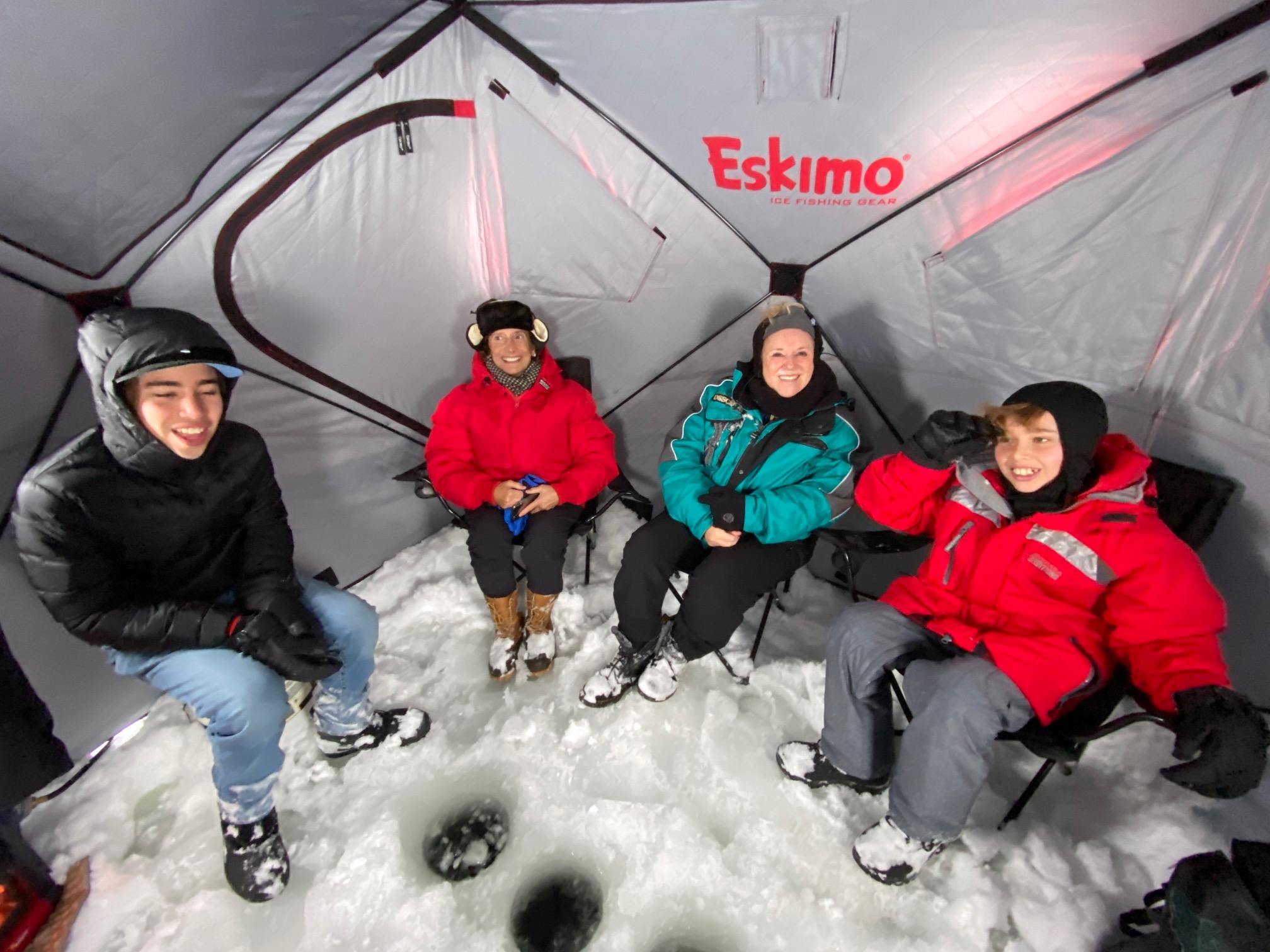 The group huddles in the shanty, away from the elements. They hang out and have some fun while they wait for the fish