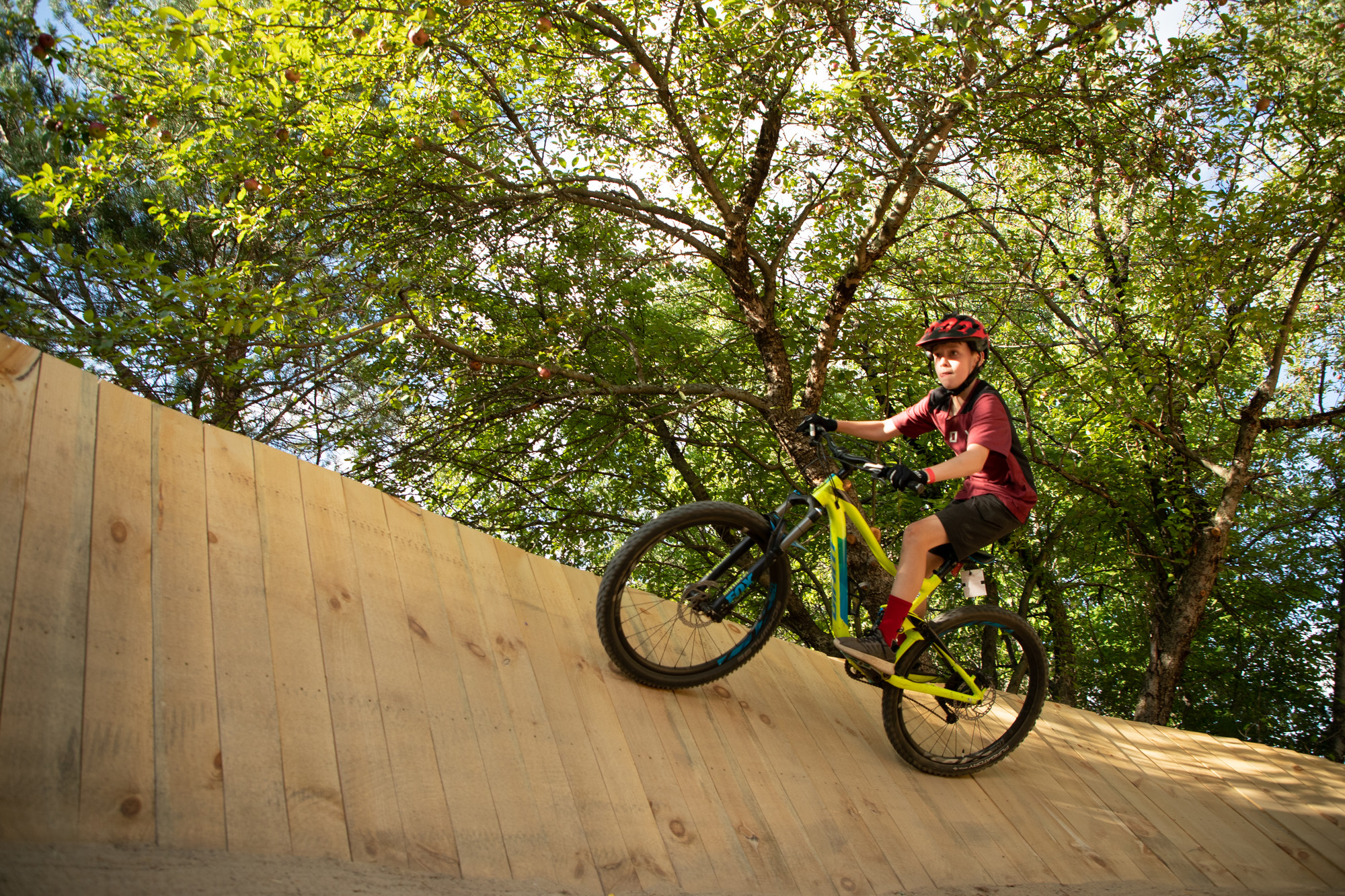 A boy focuses on riding a ramp on a bike.