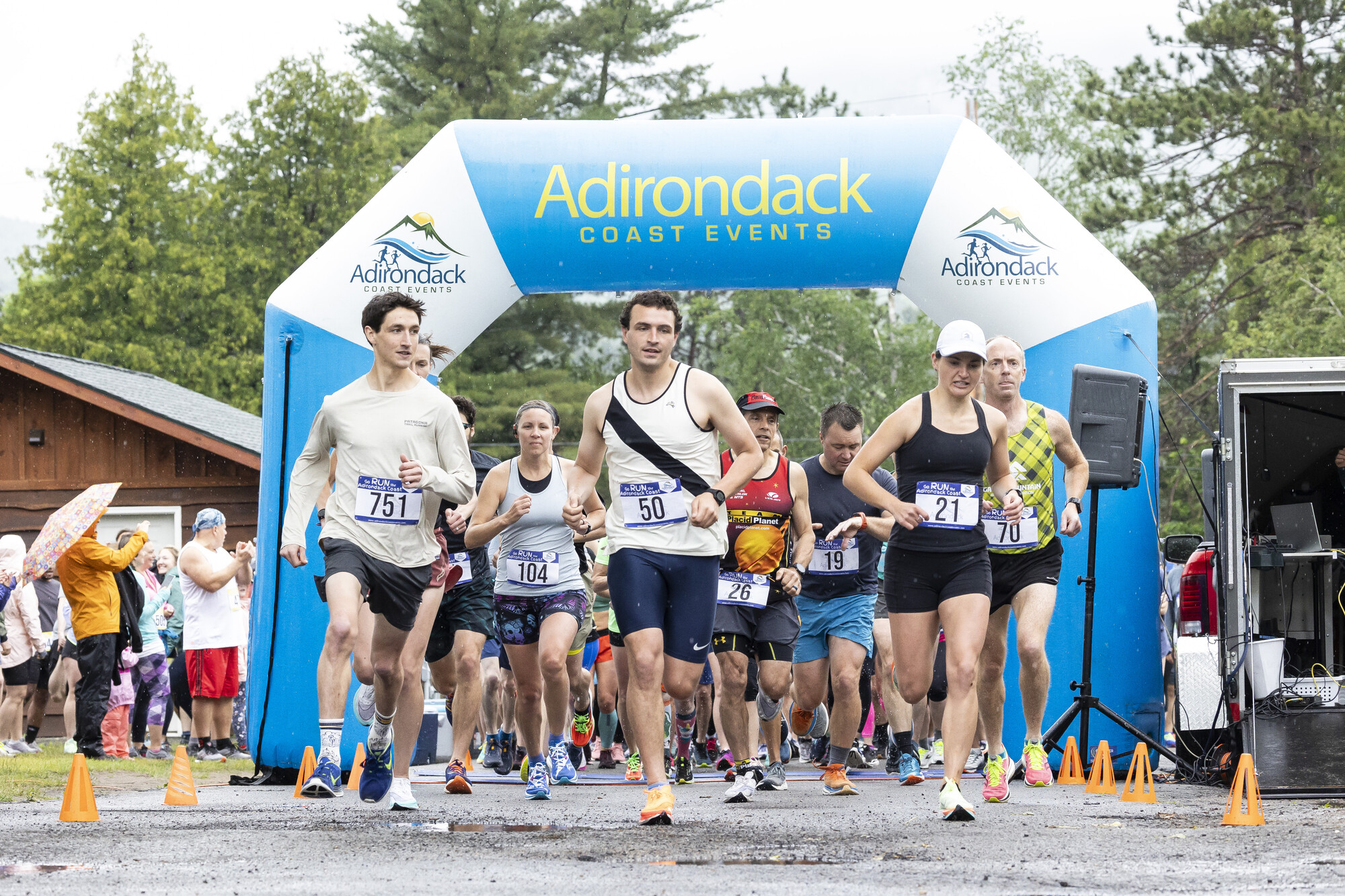 A group of runners start a race under a white amd blue archway. 