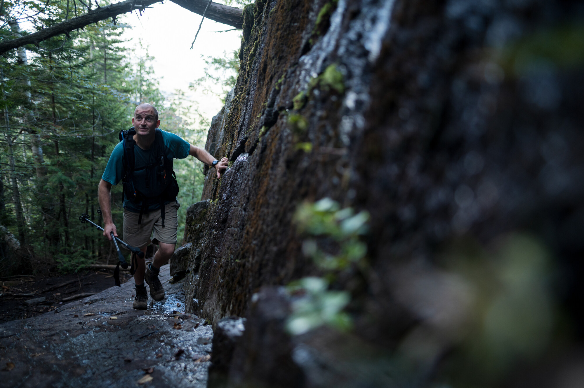 A man hikes up a narrow trail.