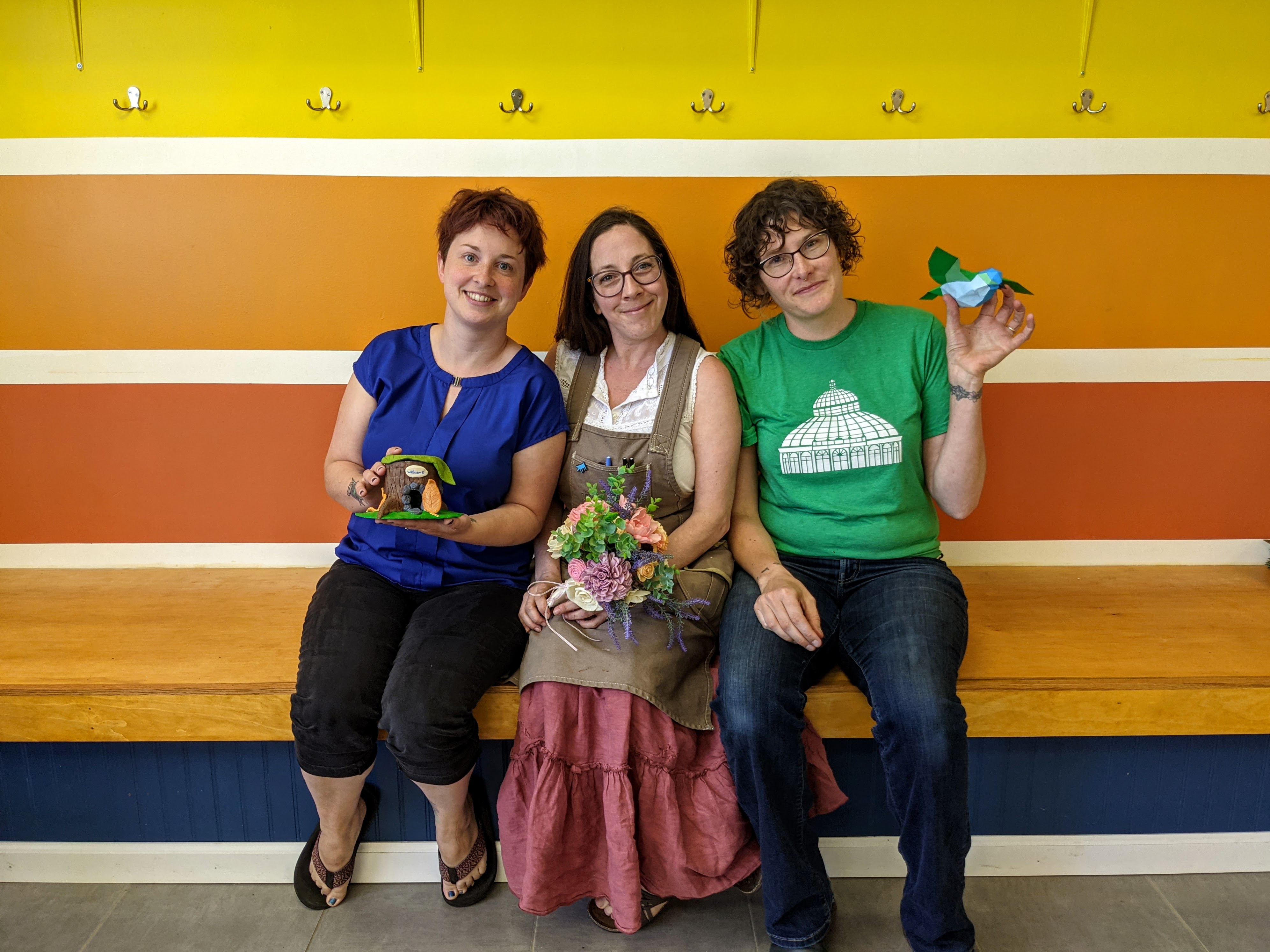 Three women sit together on a bench