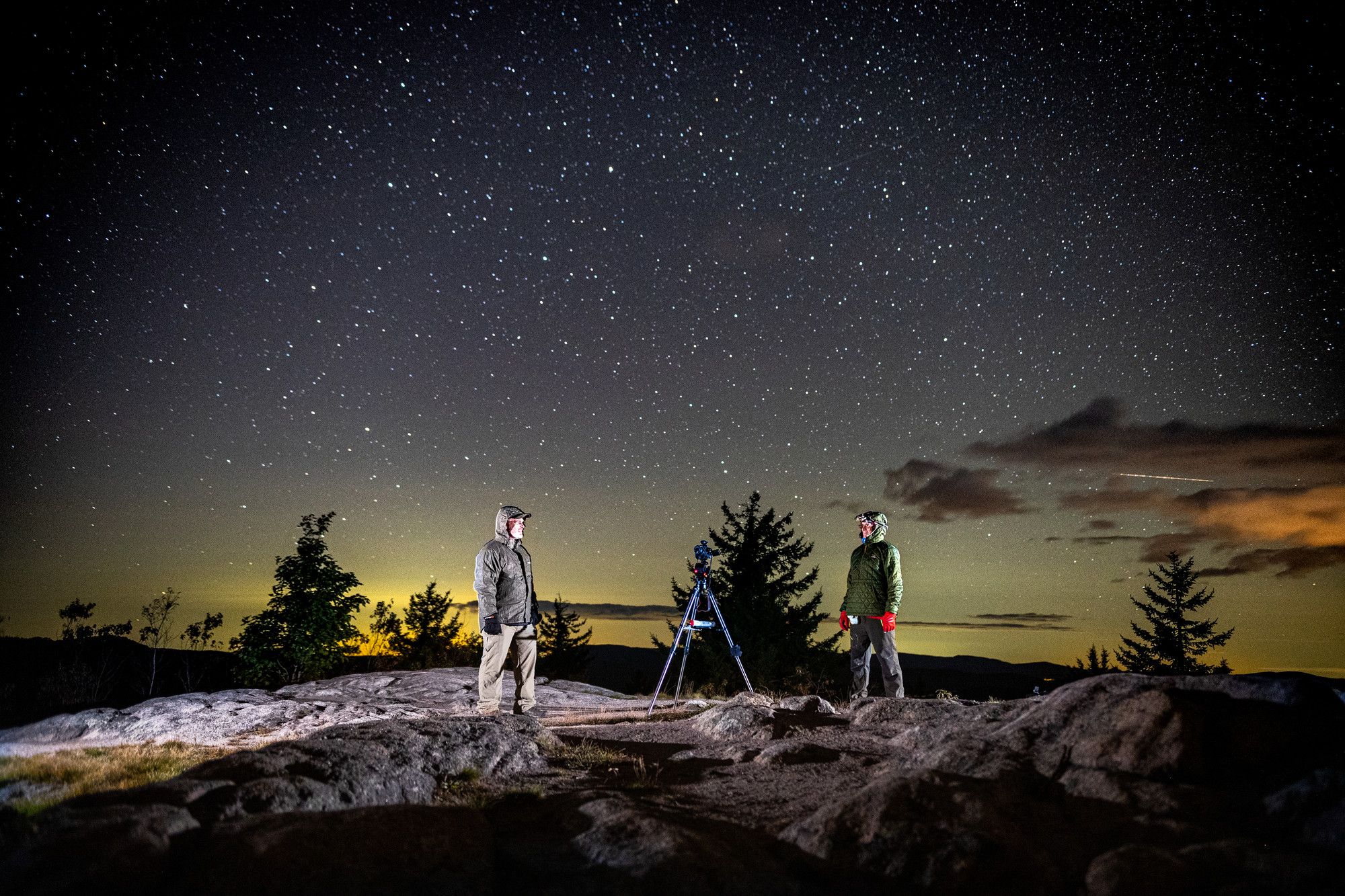 Stargazers on top of Coney Mountain with a broad night sky behind them.