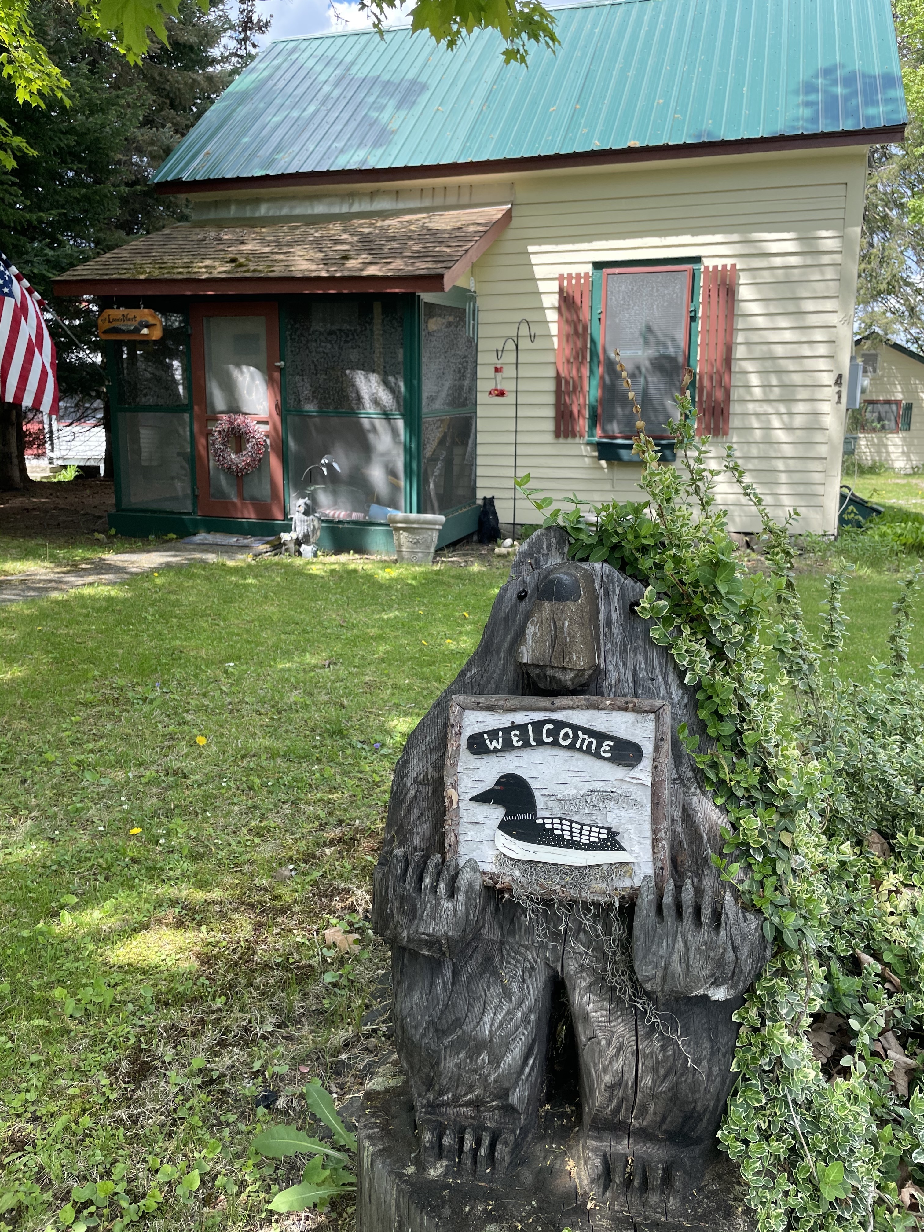 Welcome sign with a loon on it in front of a cottage.