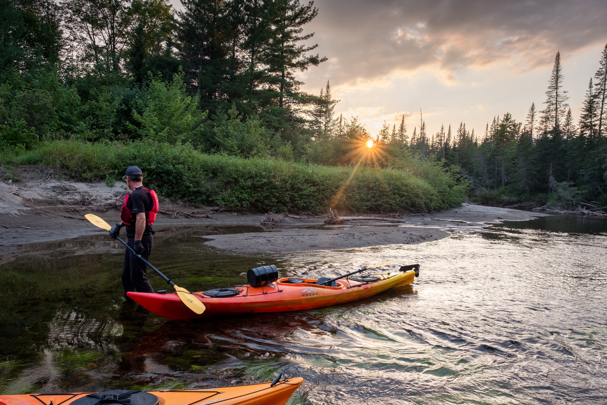 A man stands next to a kayak.