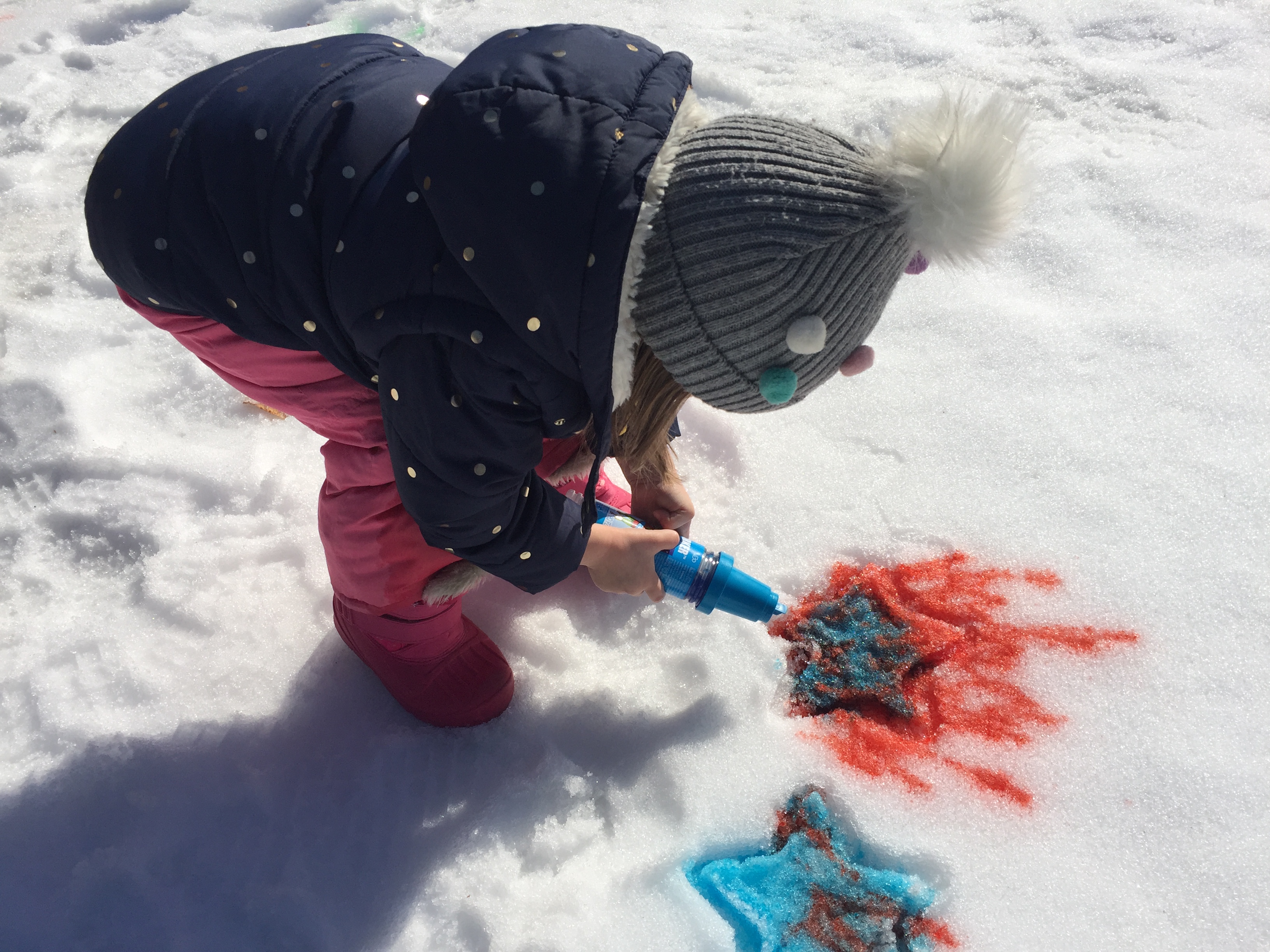 A child making colored sculptures in the snow.